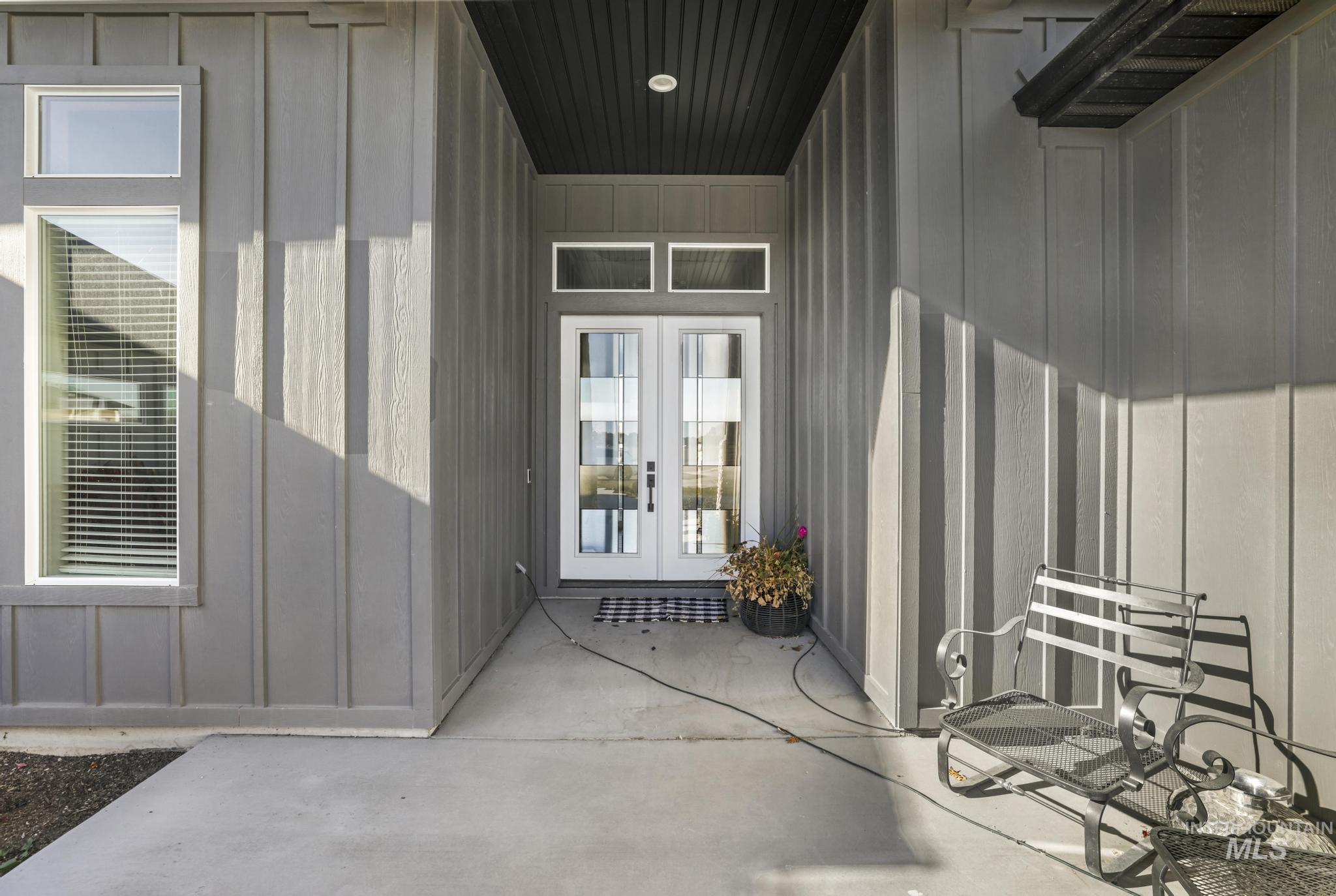 View of exterior entry with board and batten siding and a patio area
