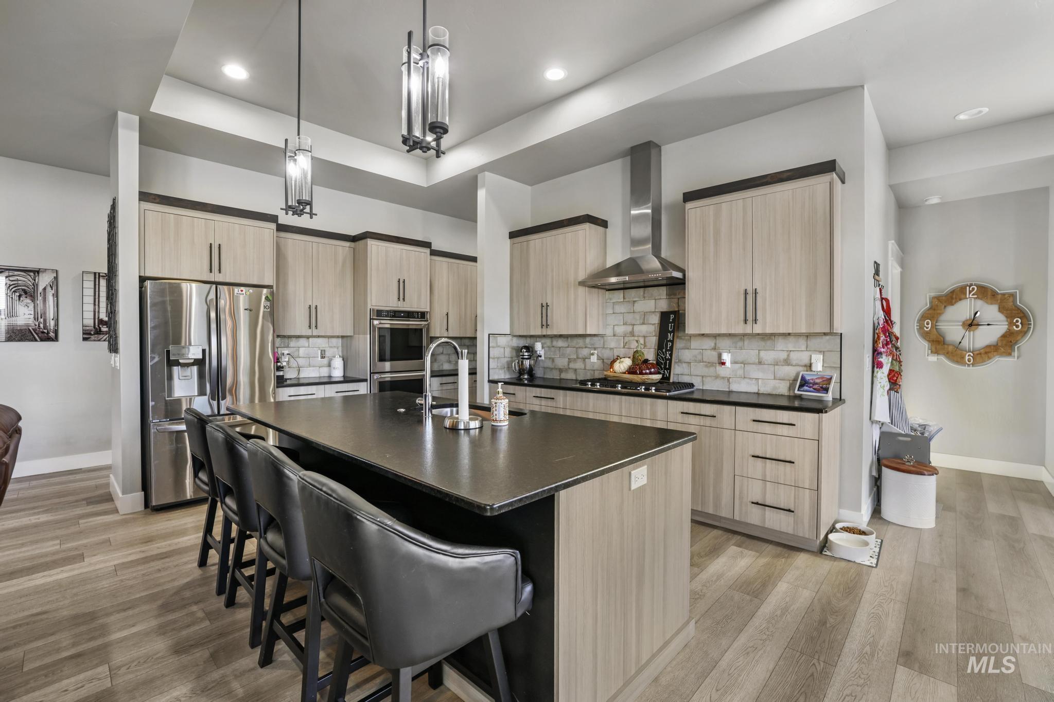 Kitchen with light brown cabinetry, an island with sink, appliances with stainless steel finishes, and recessed lighting