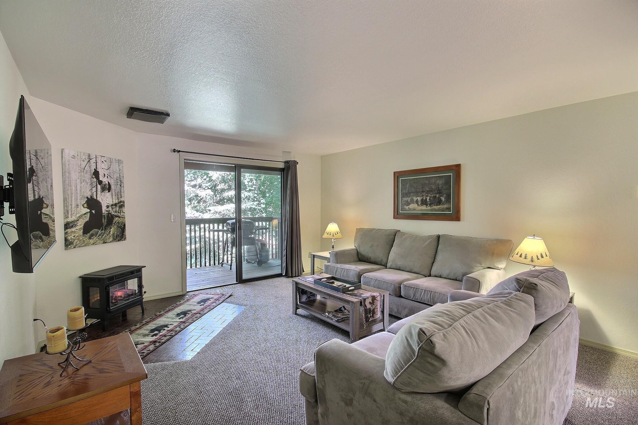 Carpeted living area with a wood stove and a textured ceiling