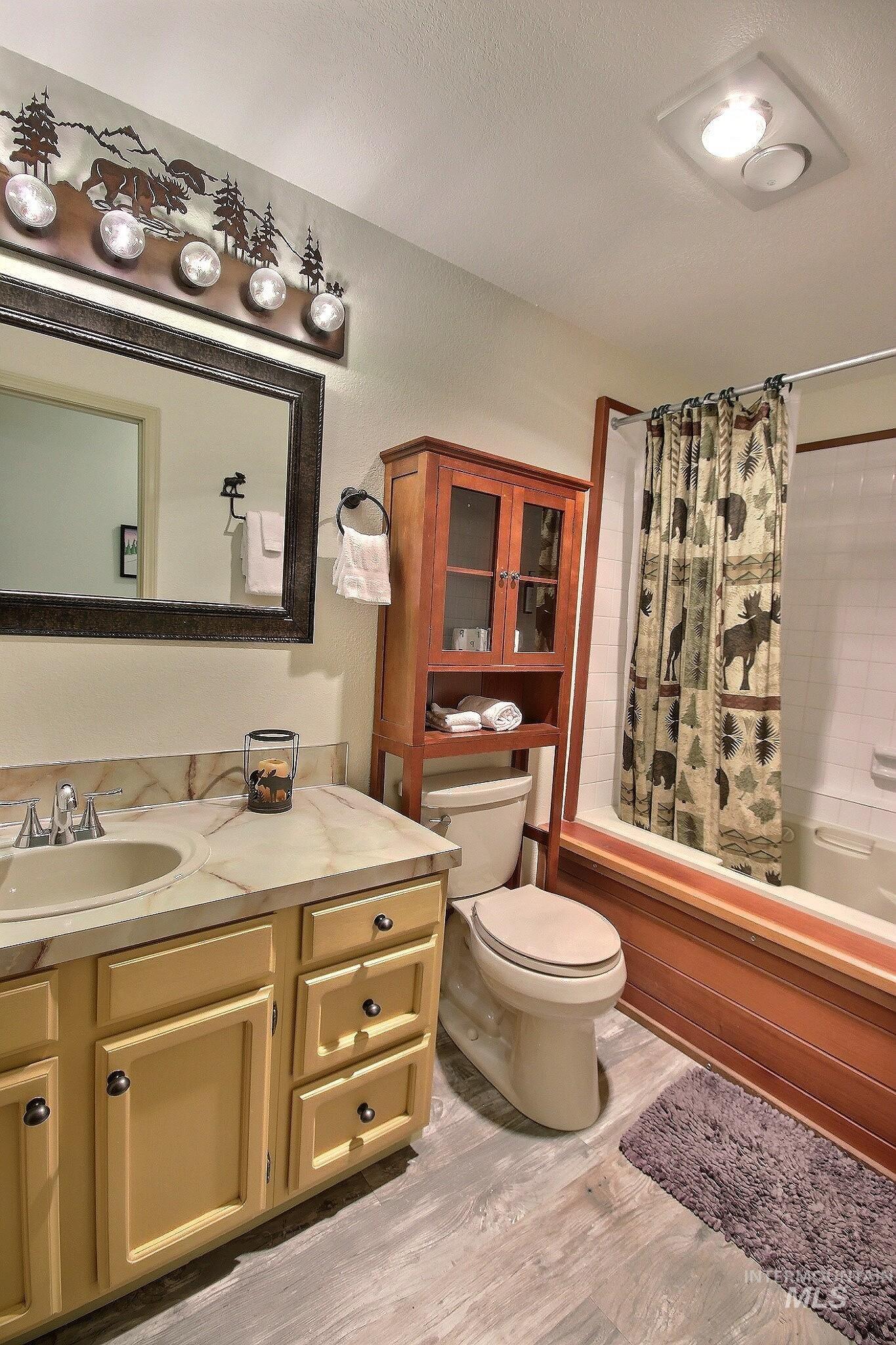 Full bathroom featuring shower / bath combination with curtain, vanity, and light wood finished floors