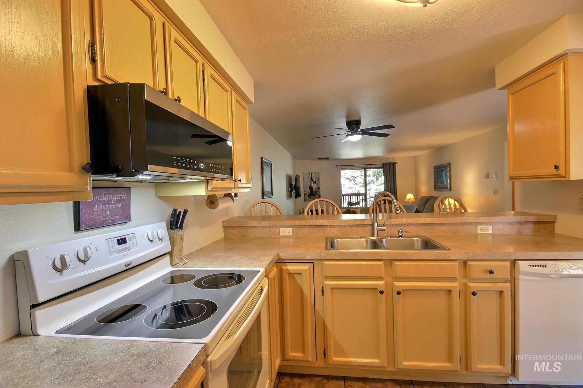 Kitchen featuring white appliances, a peninsula, light countertops, and a textured ceiling