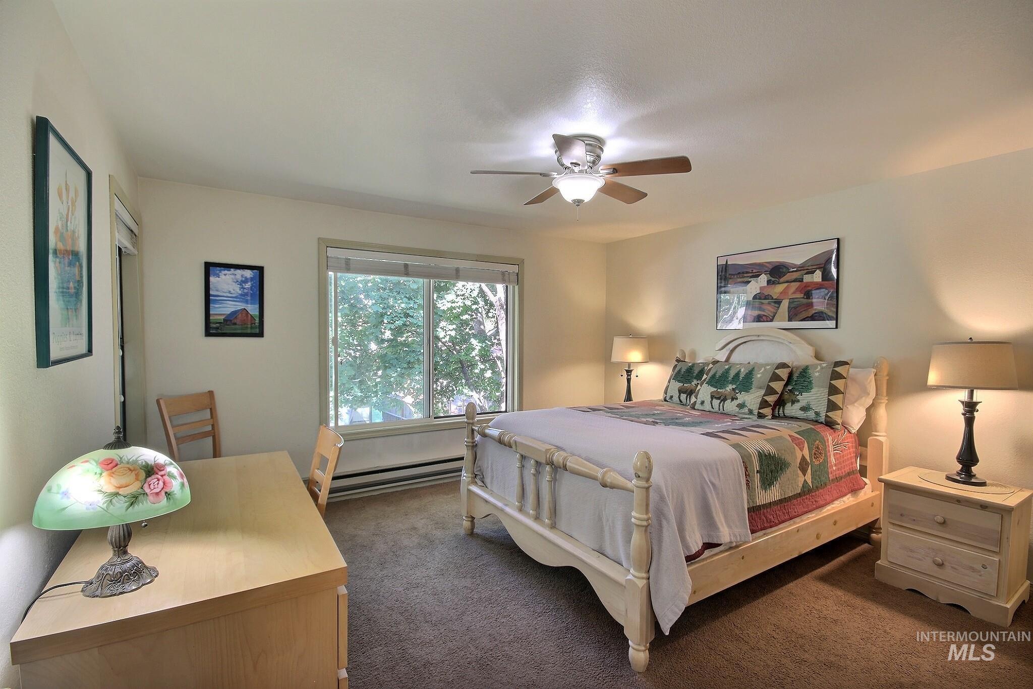 Bedroom with carpet floors, baseboard heating, and a ceiling fan