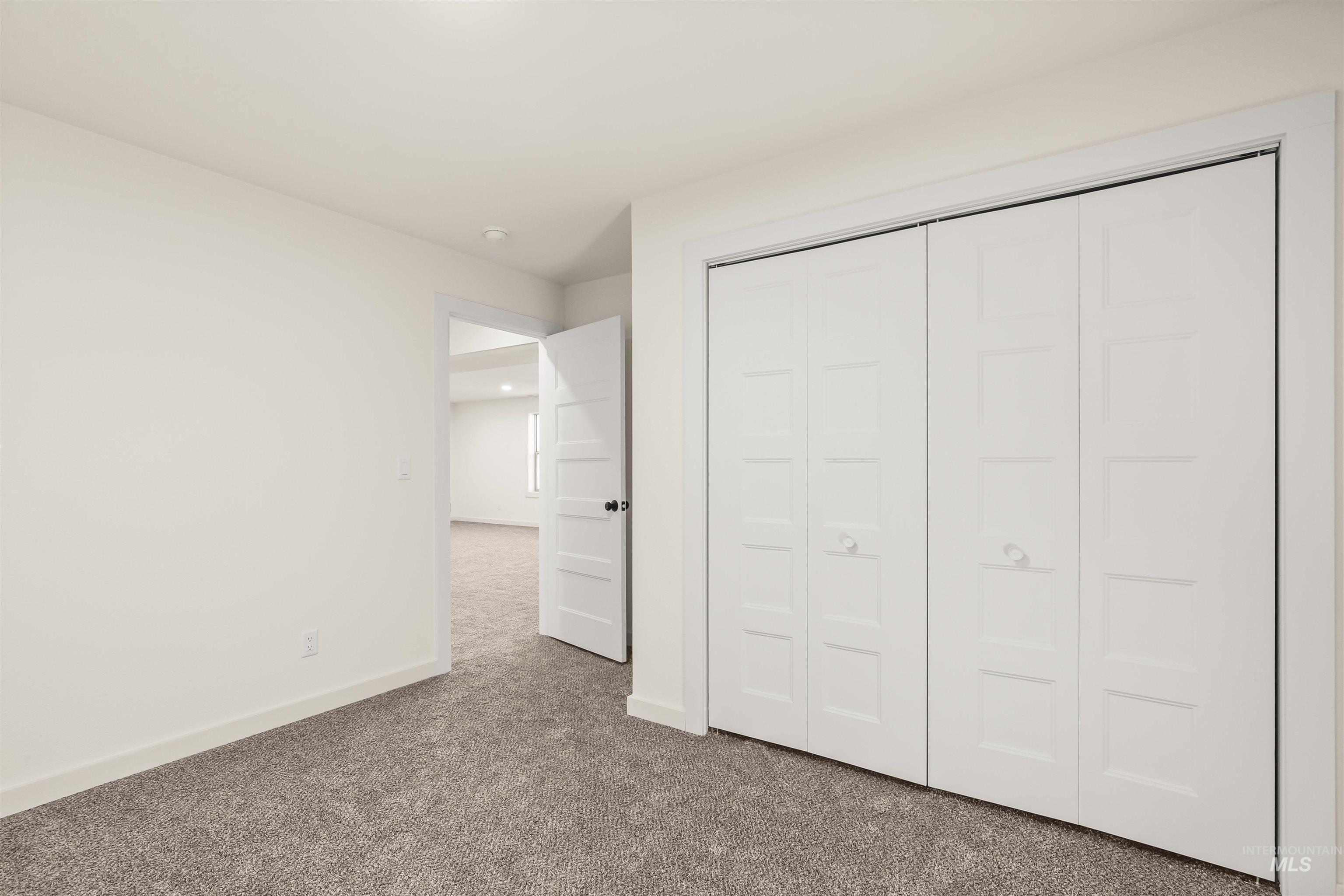 Unfurnished bedroom with dark carpet and a closet