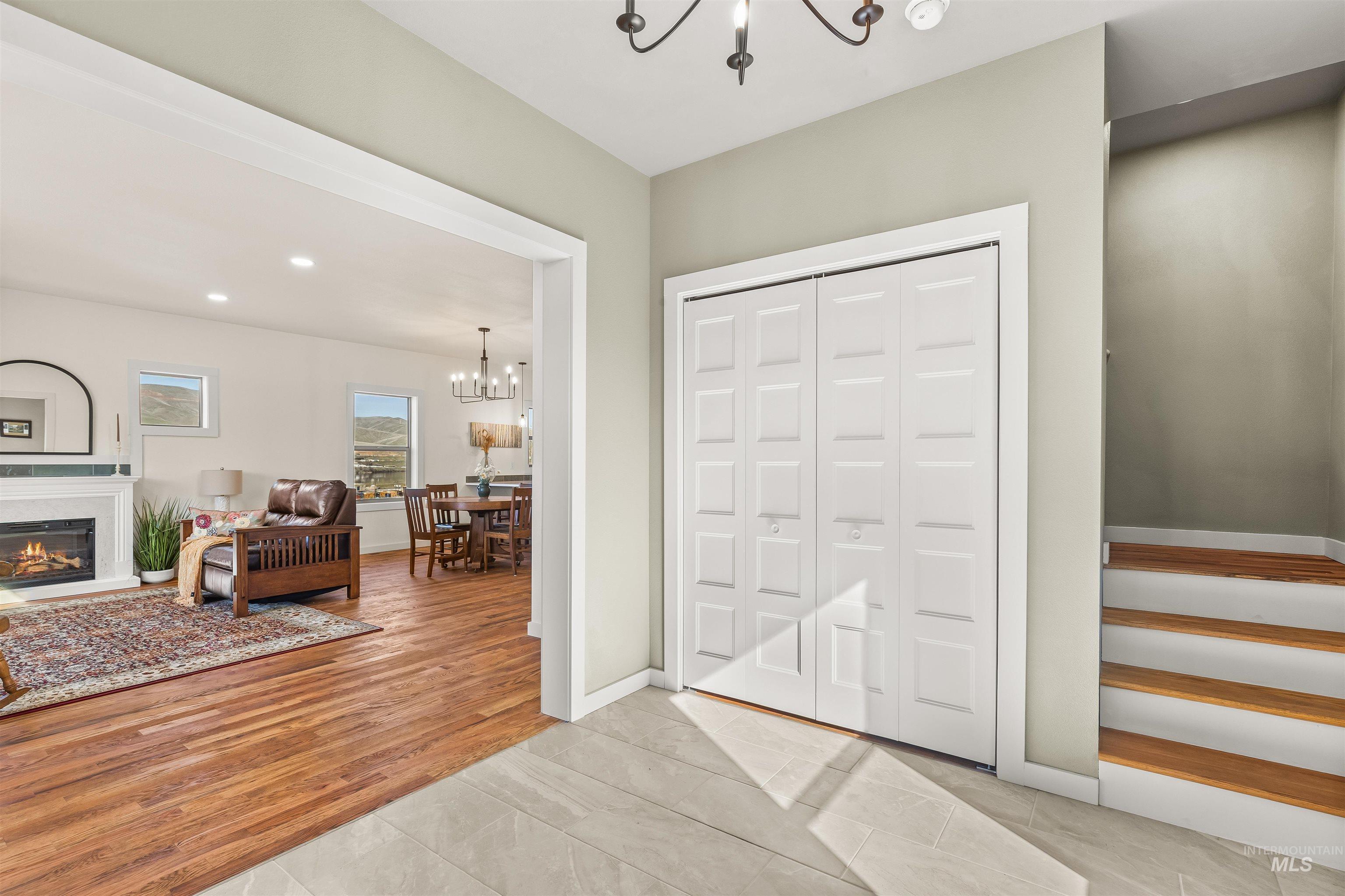 Entrance foyer with suspended lighting, light wood finished floors, and a glass covered fireplace