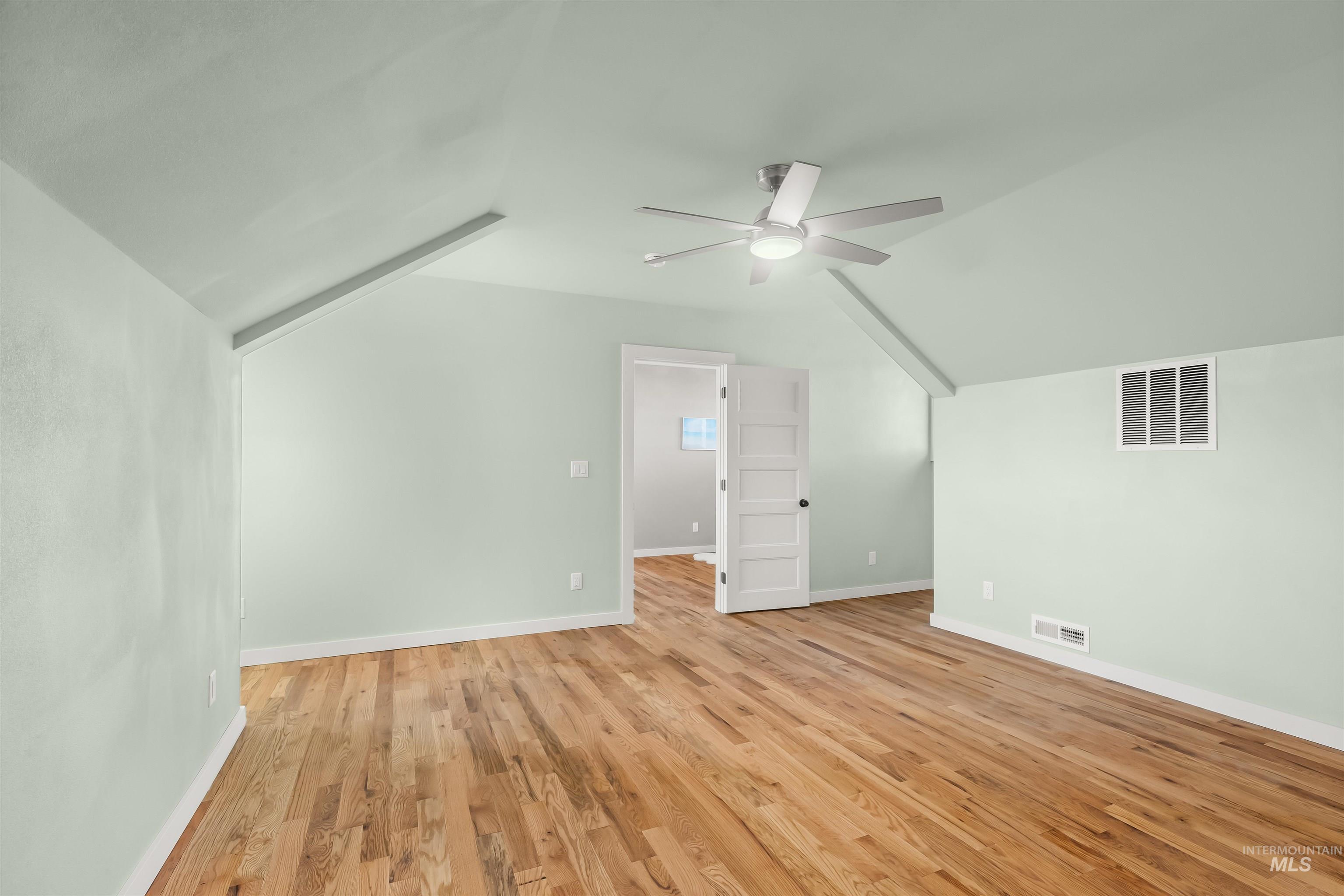 Bonus room with vaulted ceiling, light wood-style floors, and ceiling fan