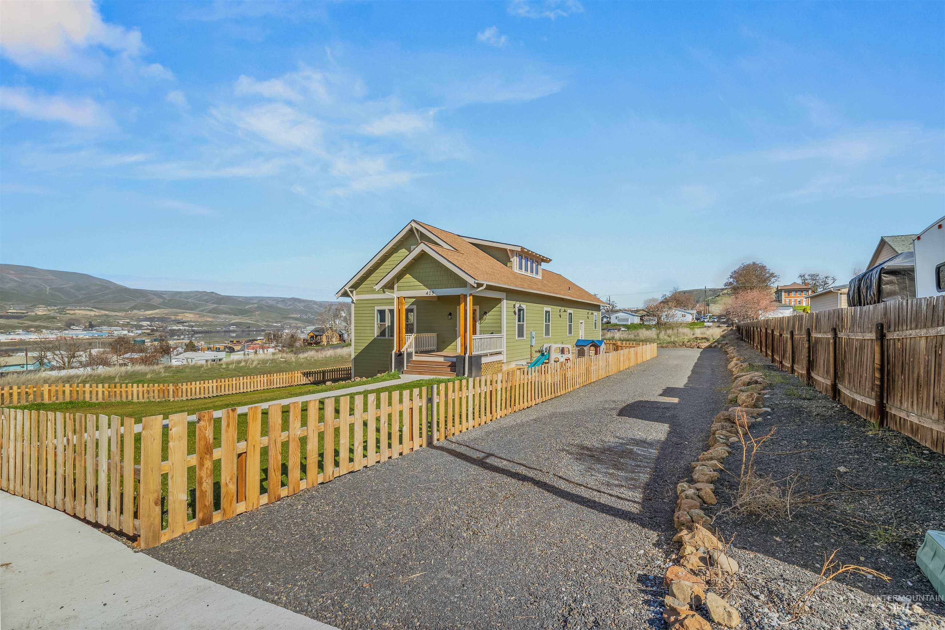 View of front of property with covered porch, a fenced front yard, a mountain view, and a residential view
