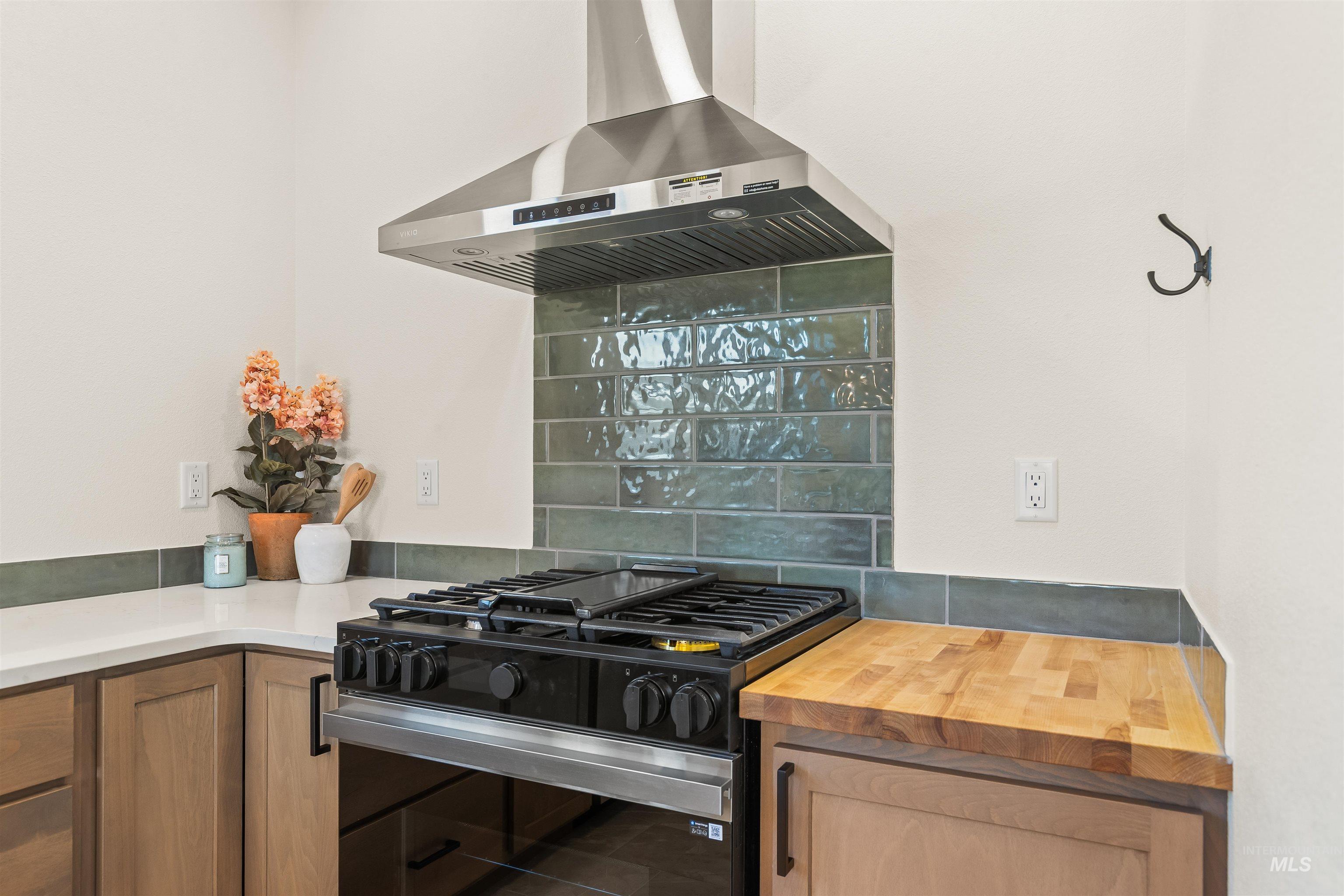 Kitchen with range with gas stovetop, island range hood, tasteful backsplash, and wood finish cabinets