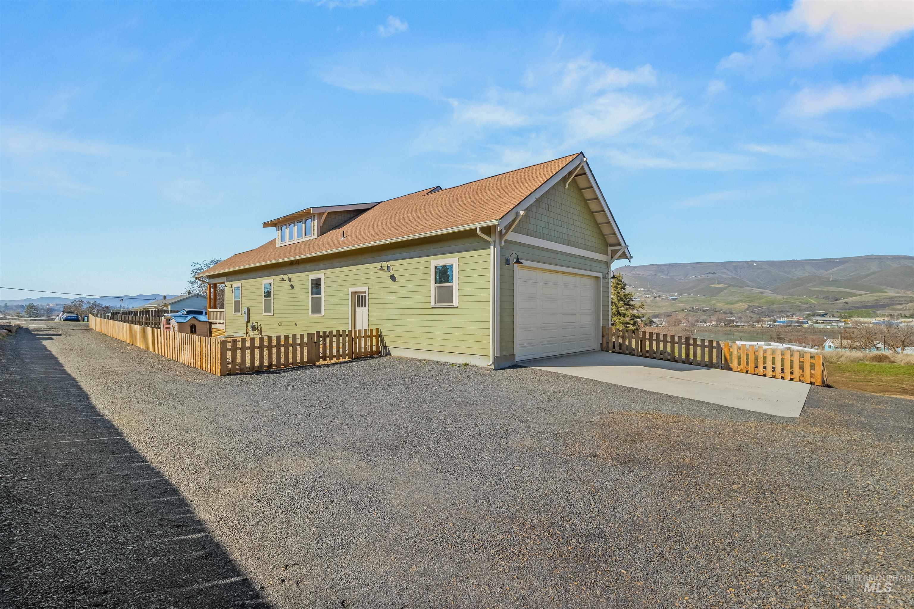 View of side of property with driveway, a mountain view, and an attached garage