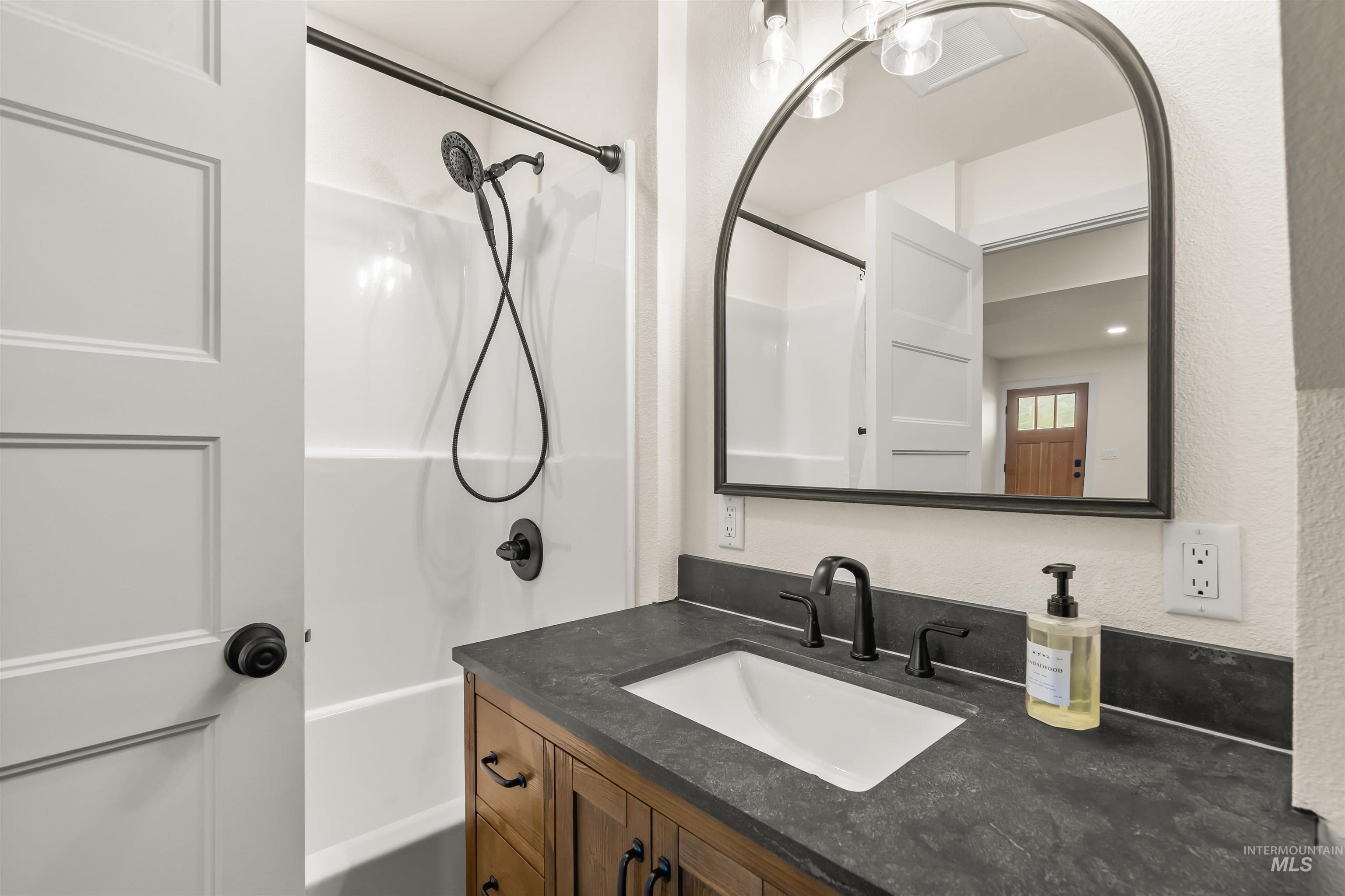 Bathroom with vanity, shower / washtub combination, and a textured wall
