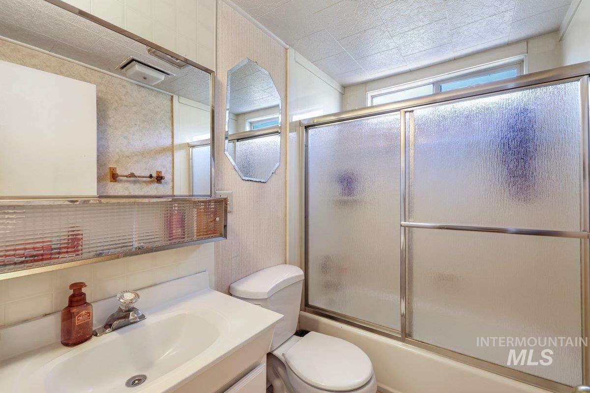 Bathroom with vanity and enclosed tub / shower combo
