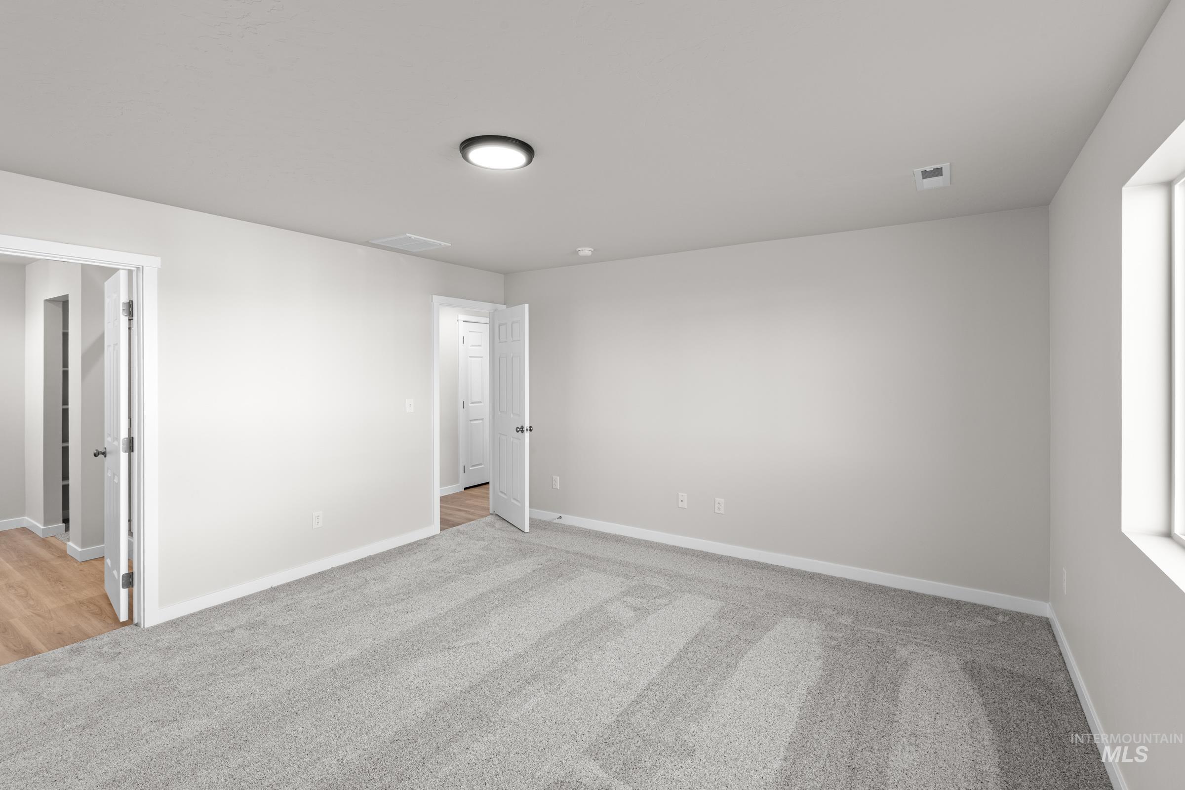 Spare room with light colored carpet and baseboards