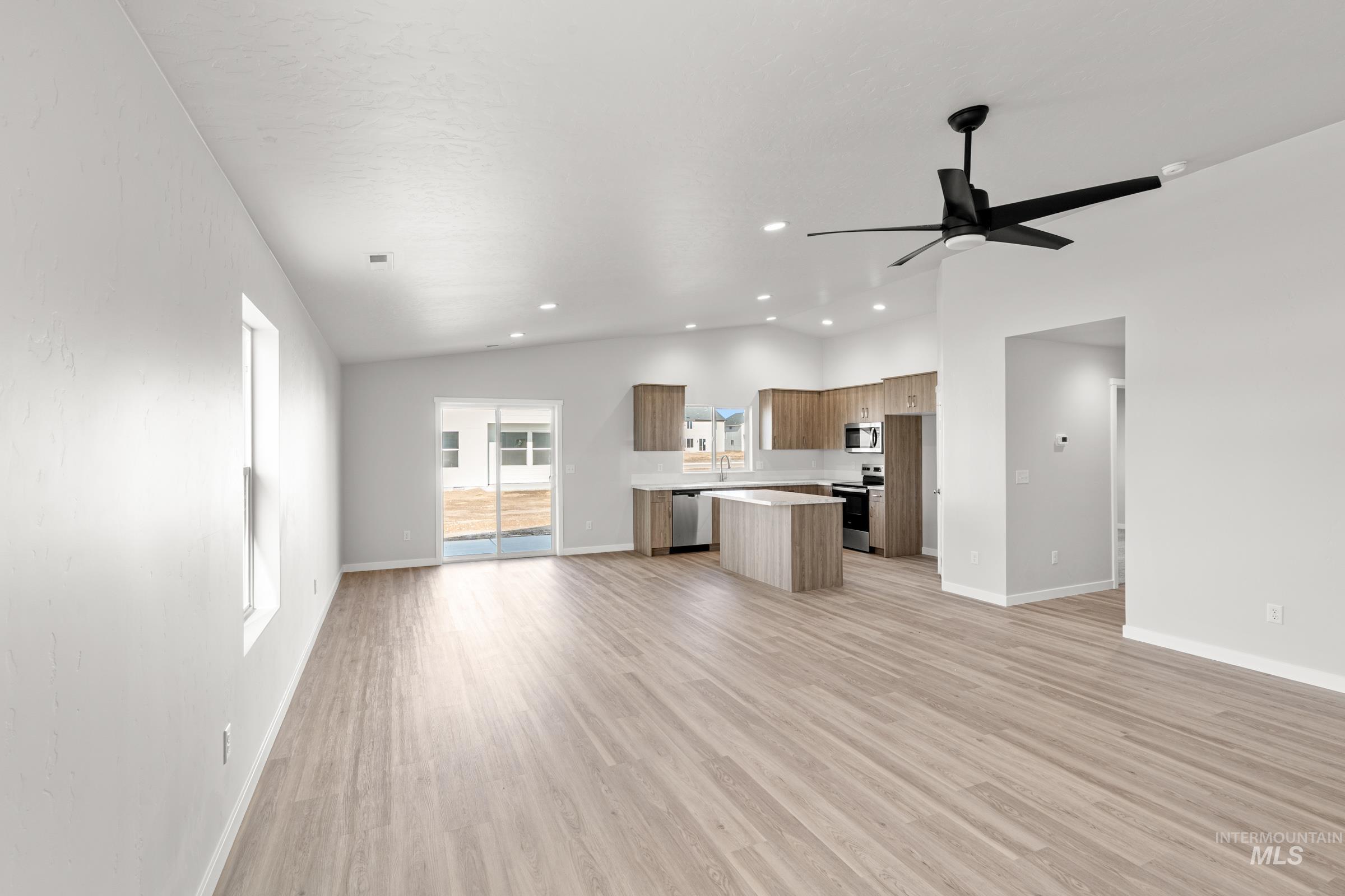 Kitchen with open floor plan, light countertops, lofted ceiling, light wood-style flooring, and a center island