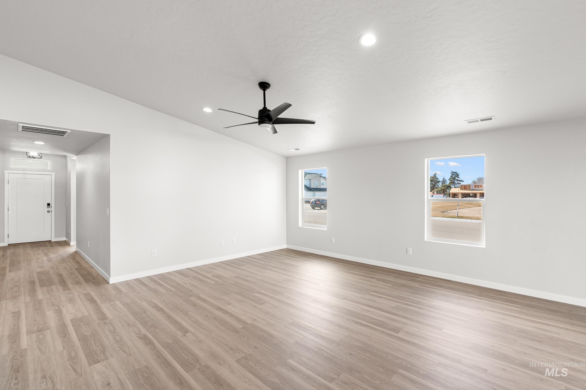 Empty room with lofted ceiling, ceiling fan, light wood-style flooring, and recessed lighting