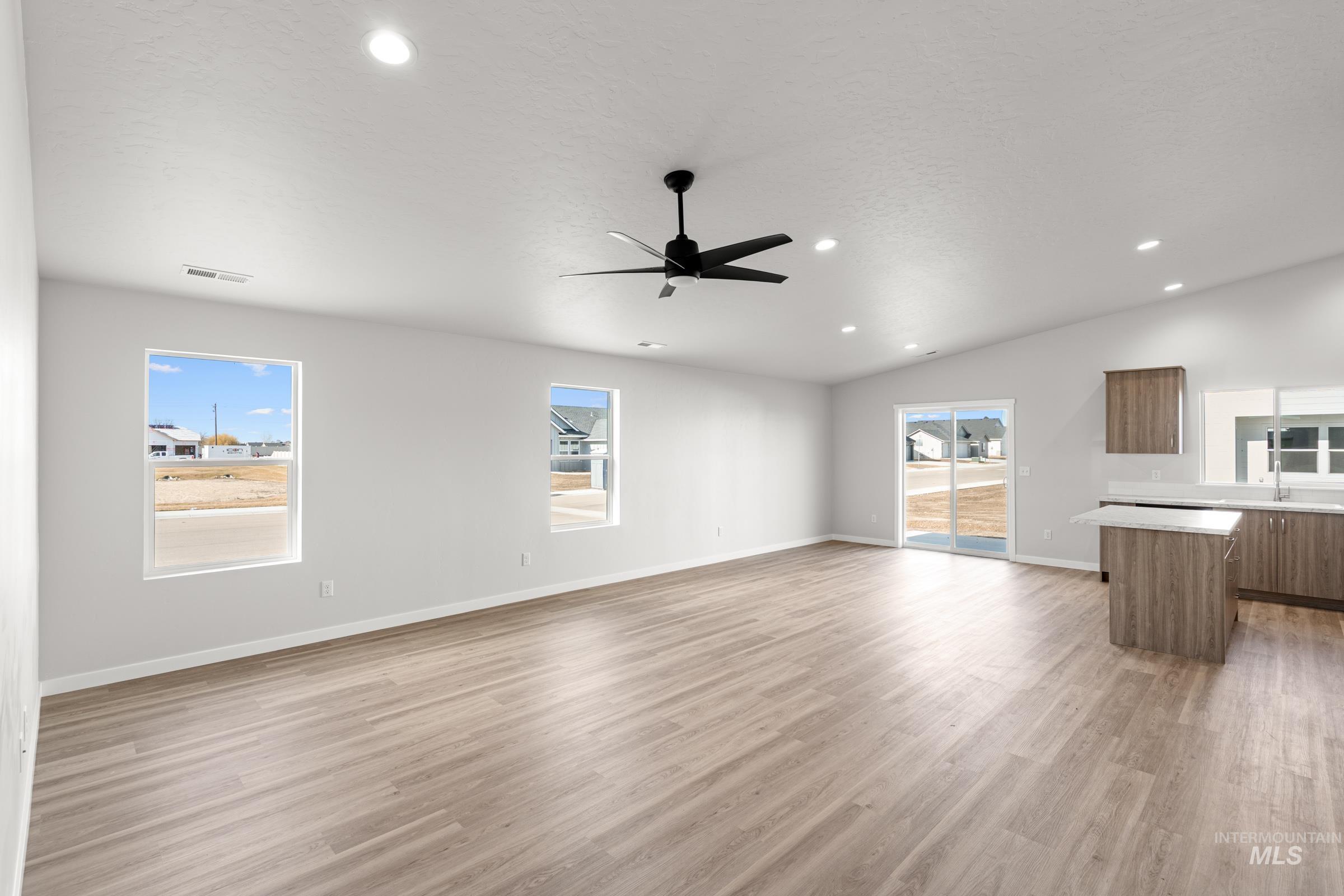 Unfurnished living room with light wood-style flooring, a ceiling fan, vaulted ceiling, and recessed lighting