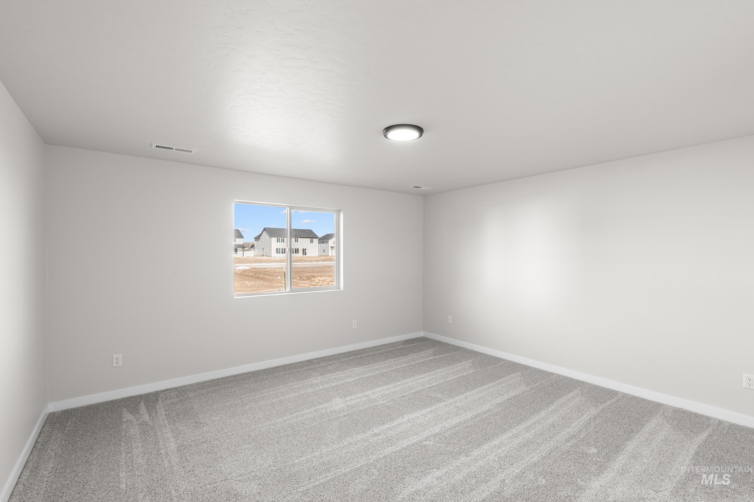 Spare room featuring light carpet and baseboards