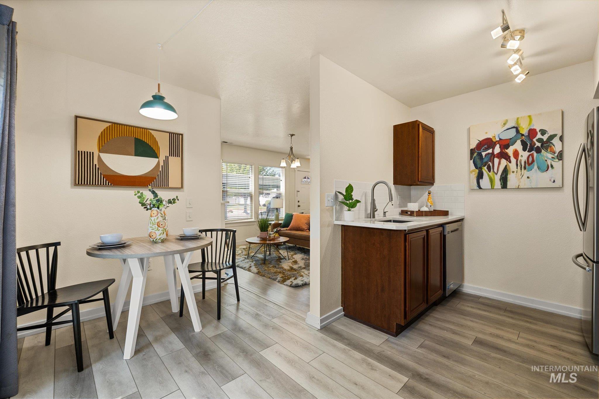 Kitchen with appliances with stainless steel finishes, light countertops, light wood-style flooring, and pendant lighting