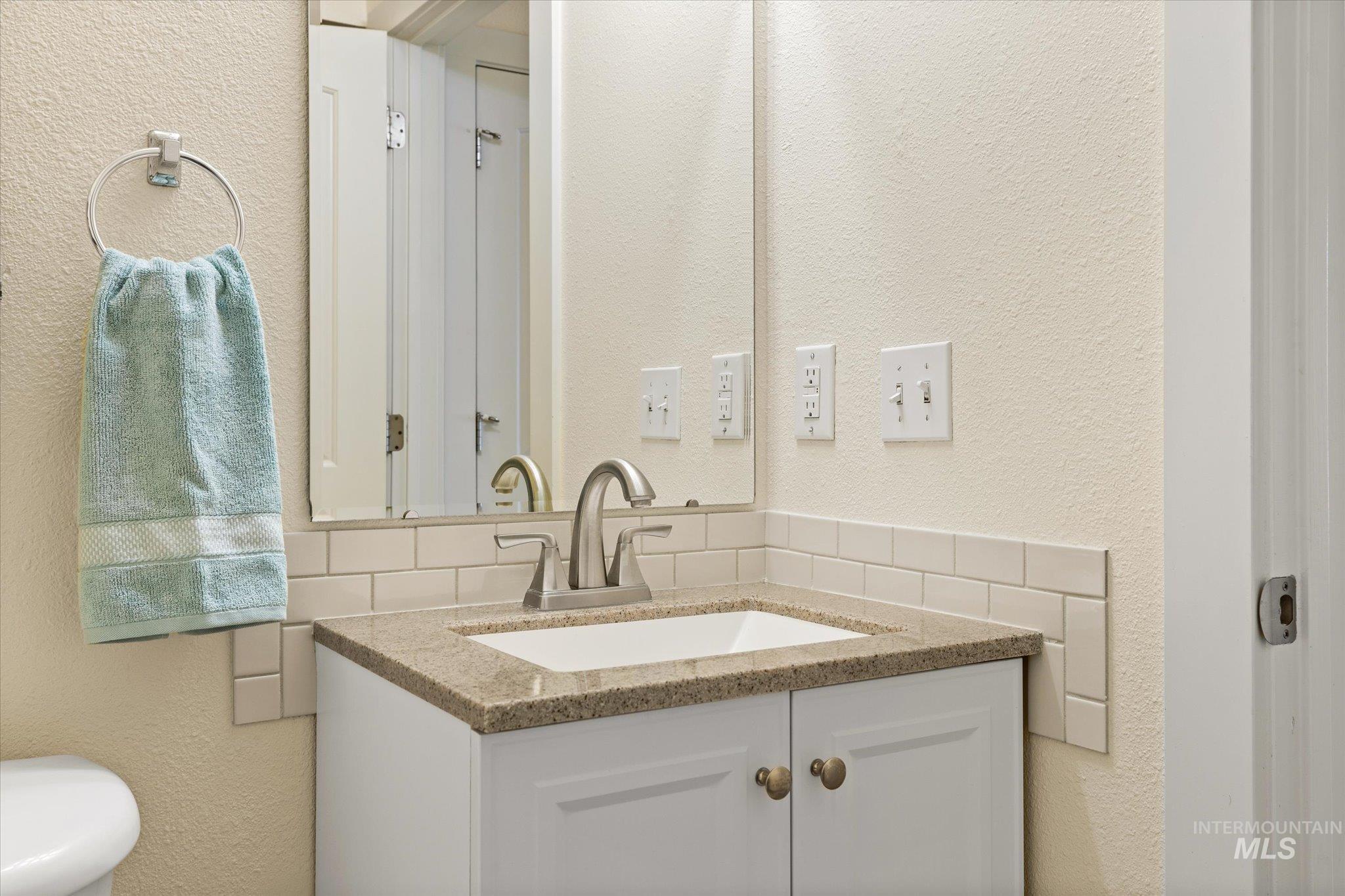 Bathroom with vanity and tasteful backsplash