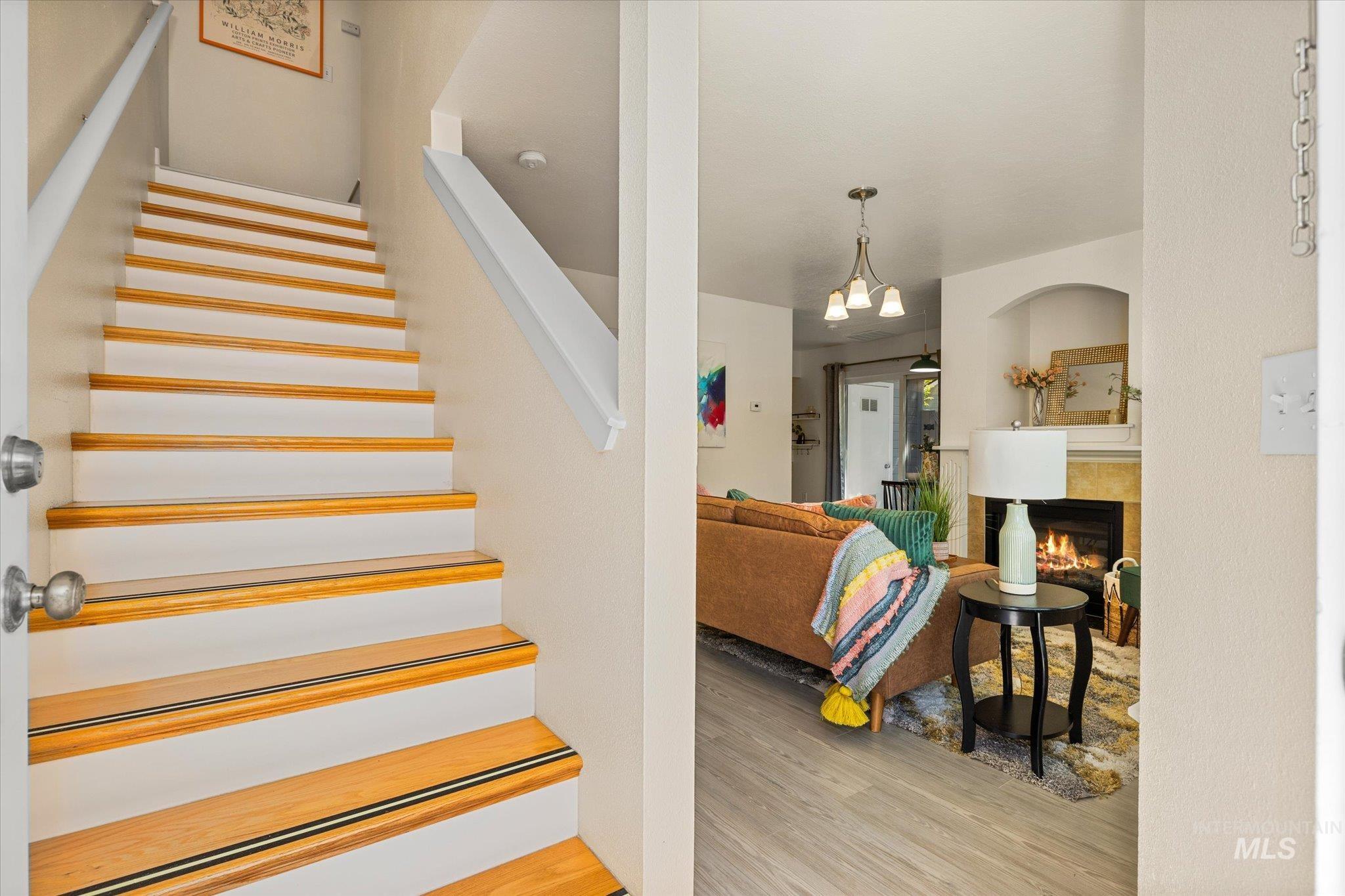 Stairway with wood finished floors and a tiled fireplace