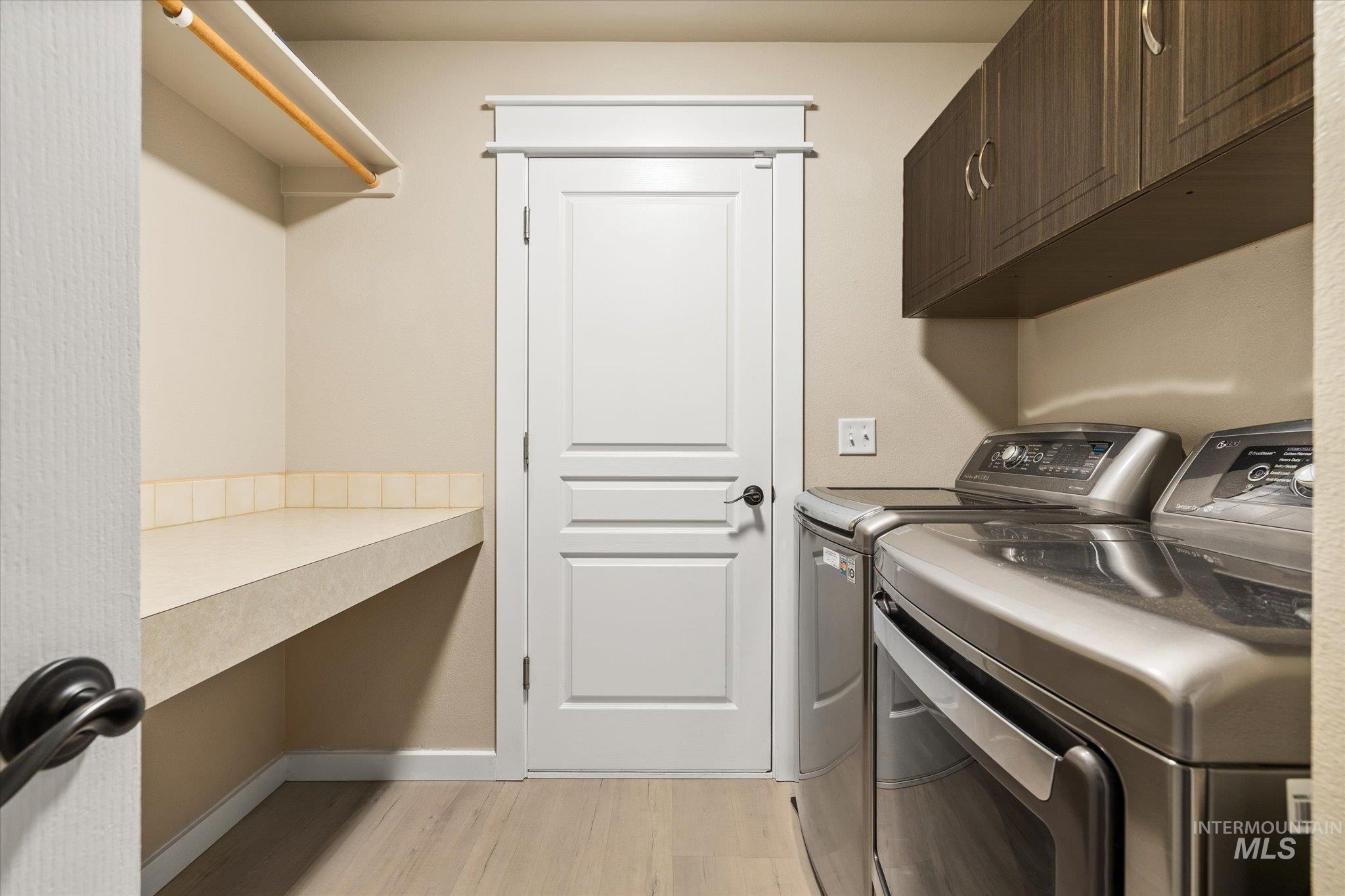 Laundry area with separate washer and dryer and light wood-type flooring