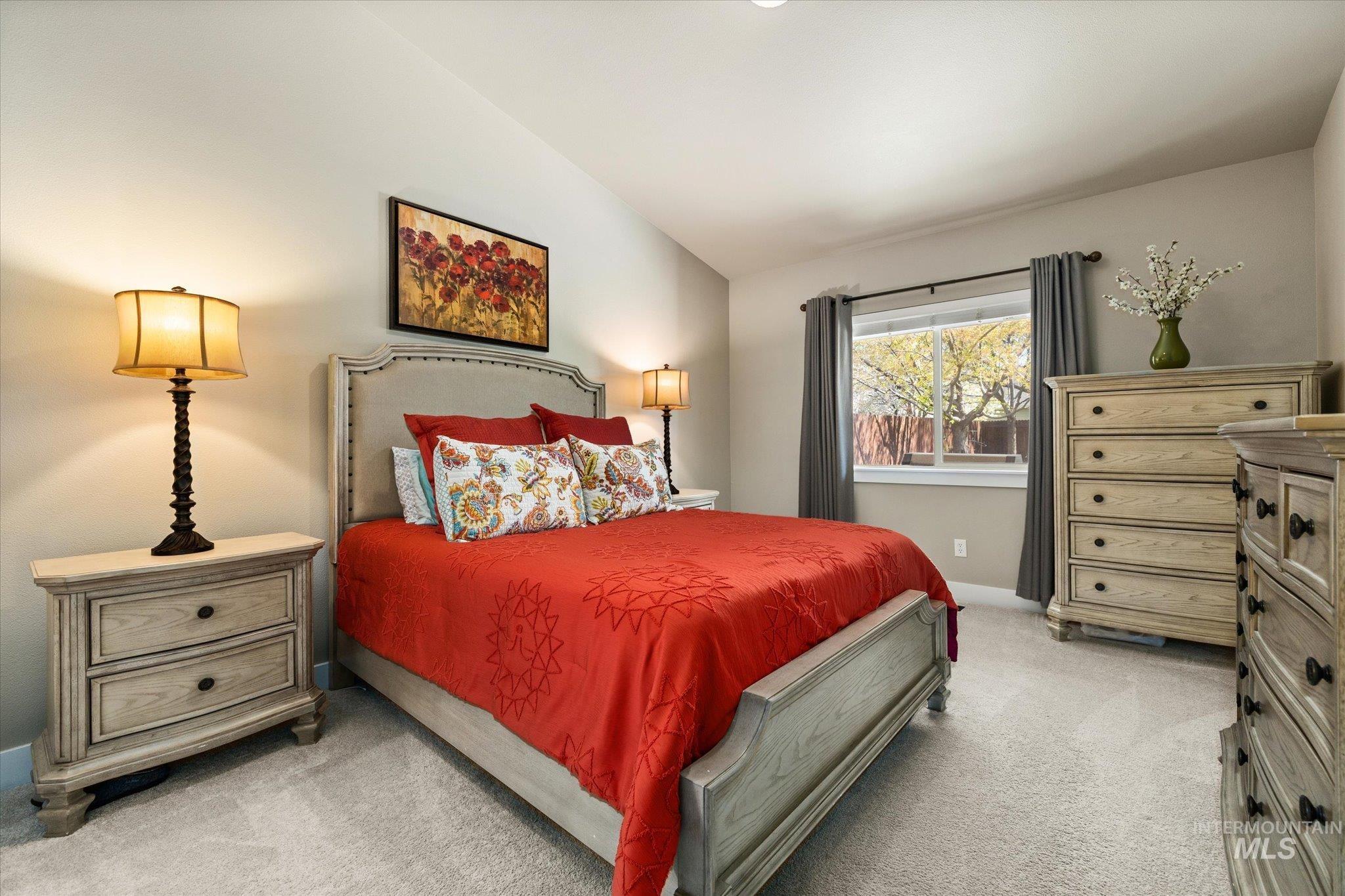 Bedroom with light colored carpet and lofted ceiling