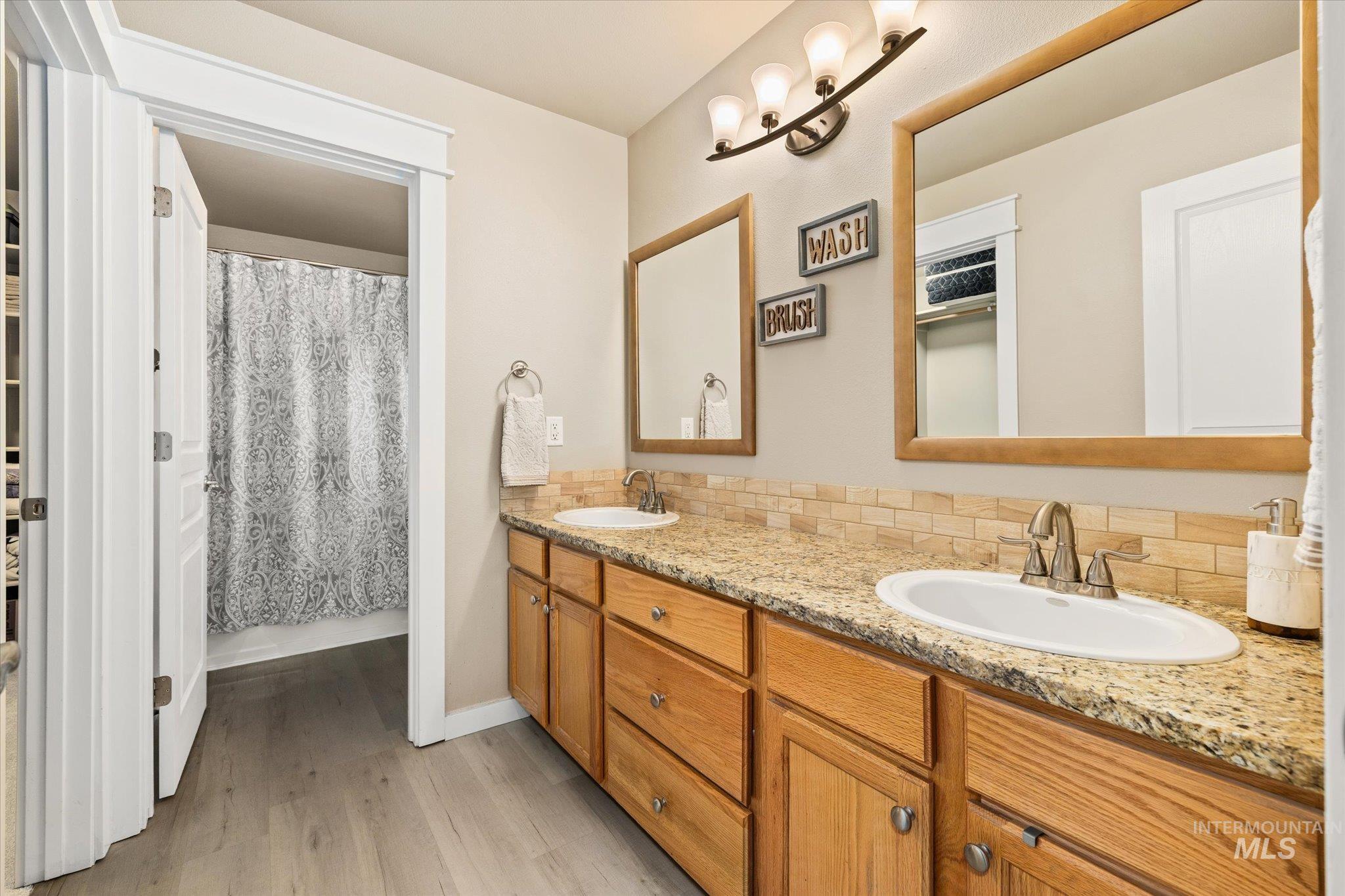 Bathroom featuring double vanity and light wood finished floors