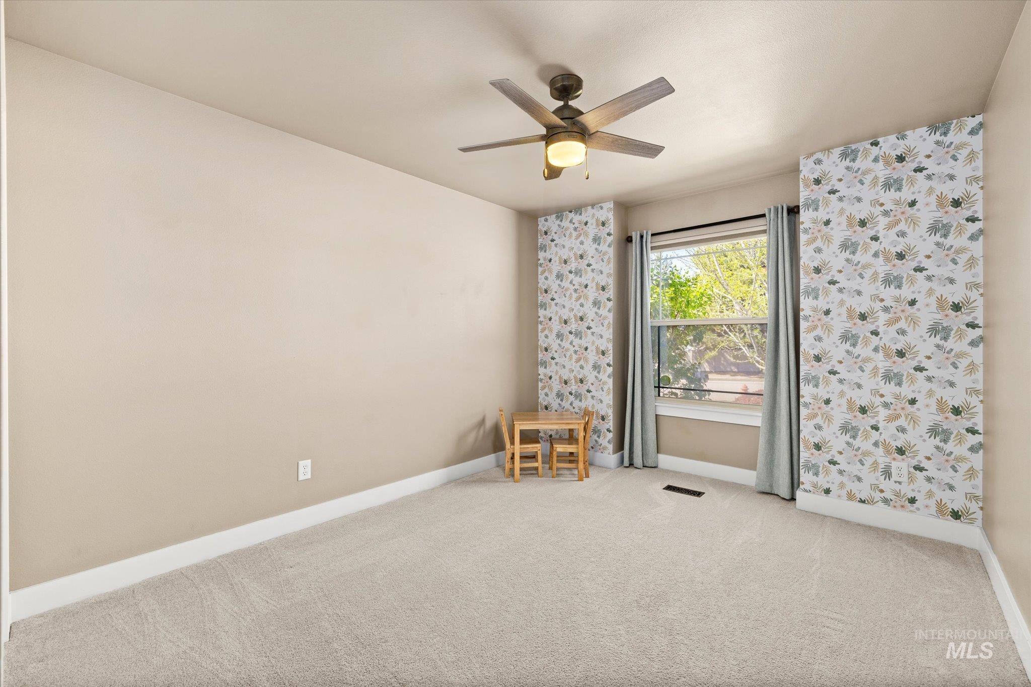Spare room featuring light carpet and ceiling fan
