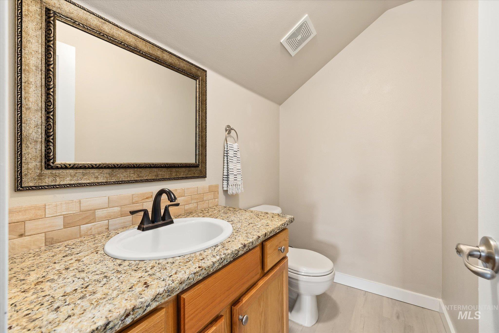 Bathroom featuring vaulted ceiling, vanity, and light wood-style floors