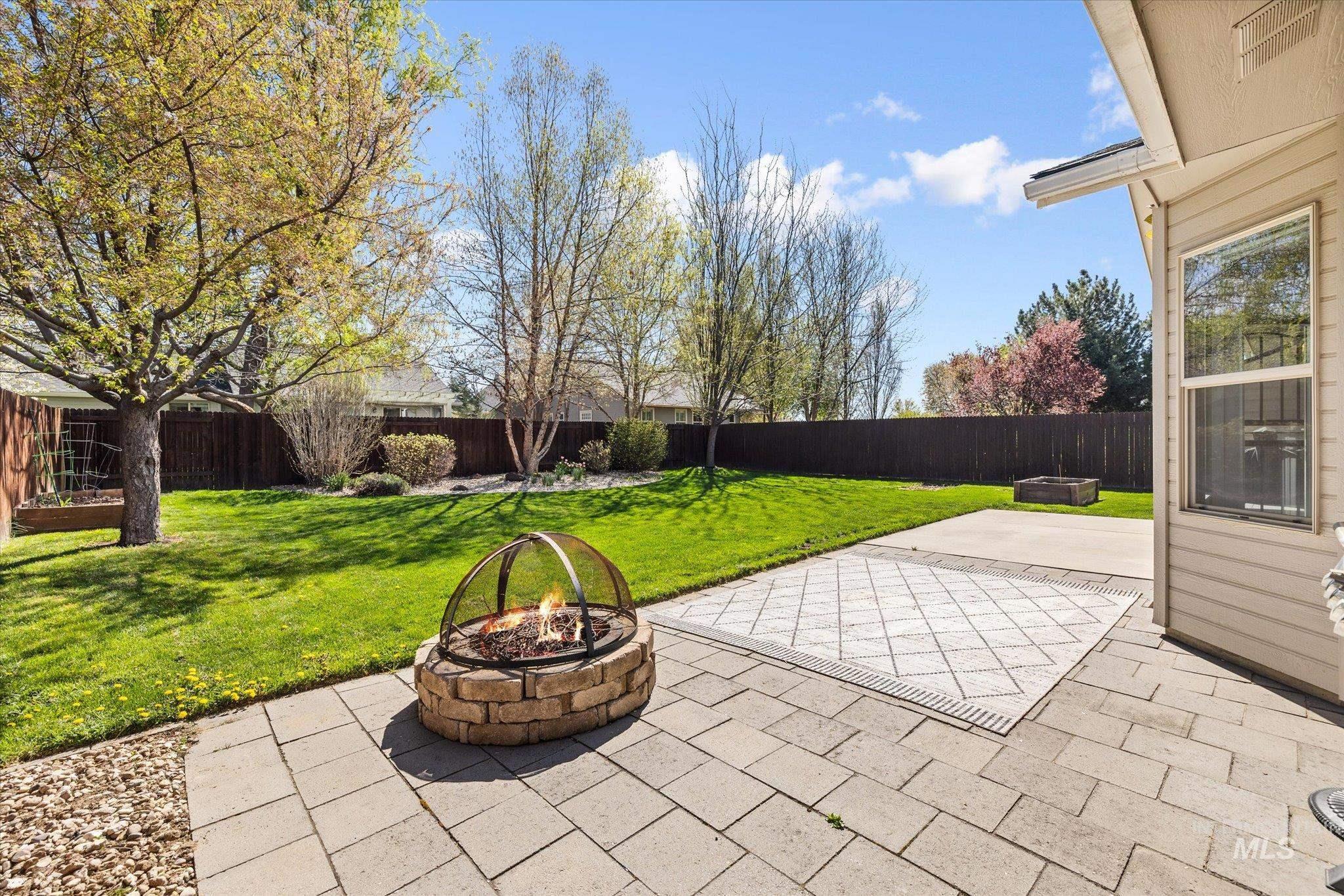 Fenced backyard featuring a fire pit and a patio