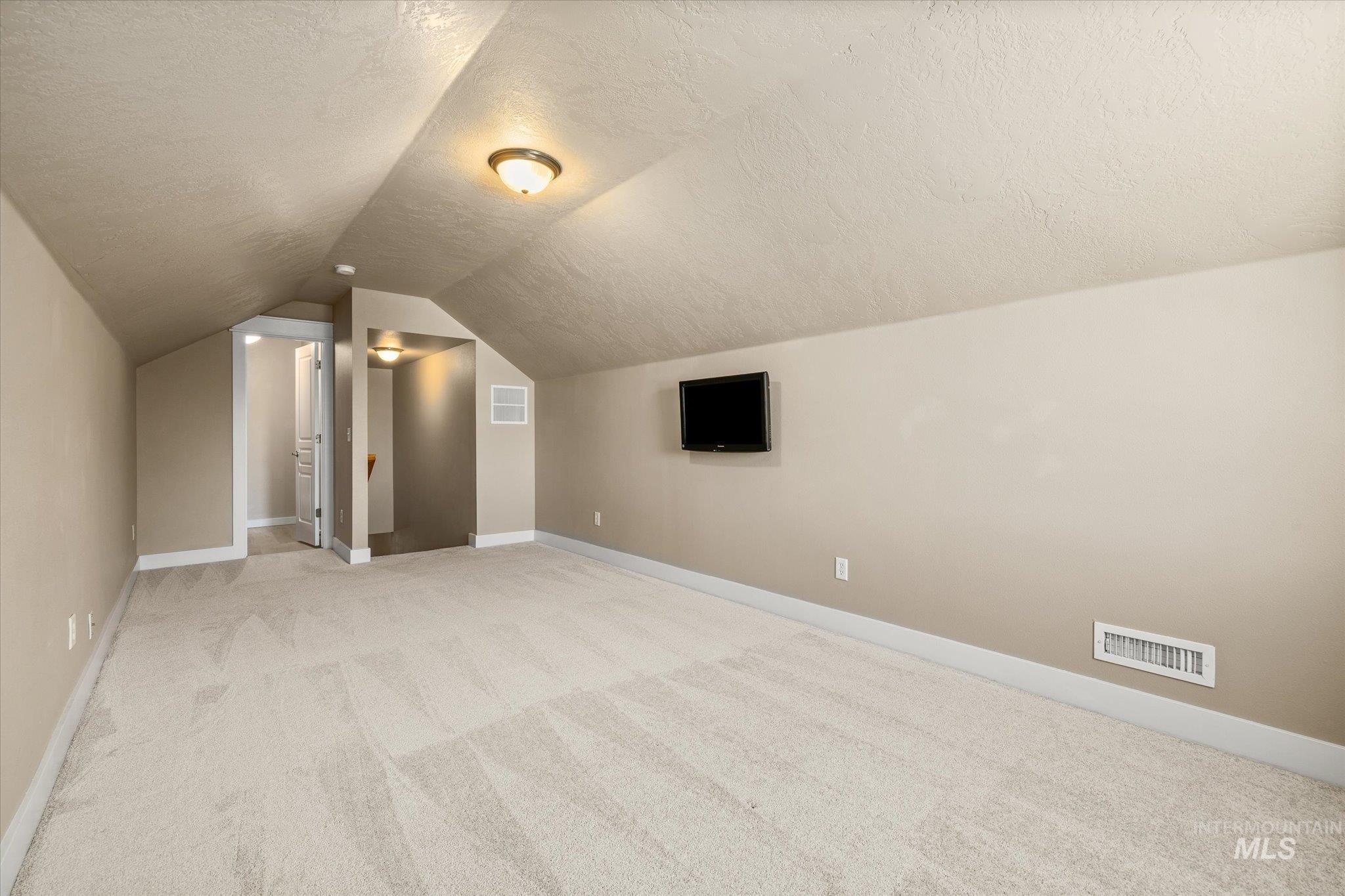 Additional living space with a textured ceiling and light colored carpet