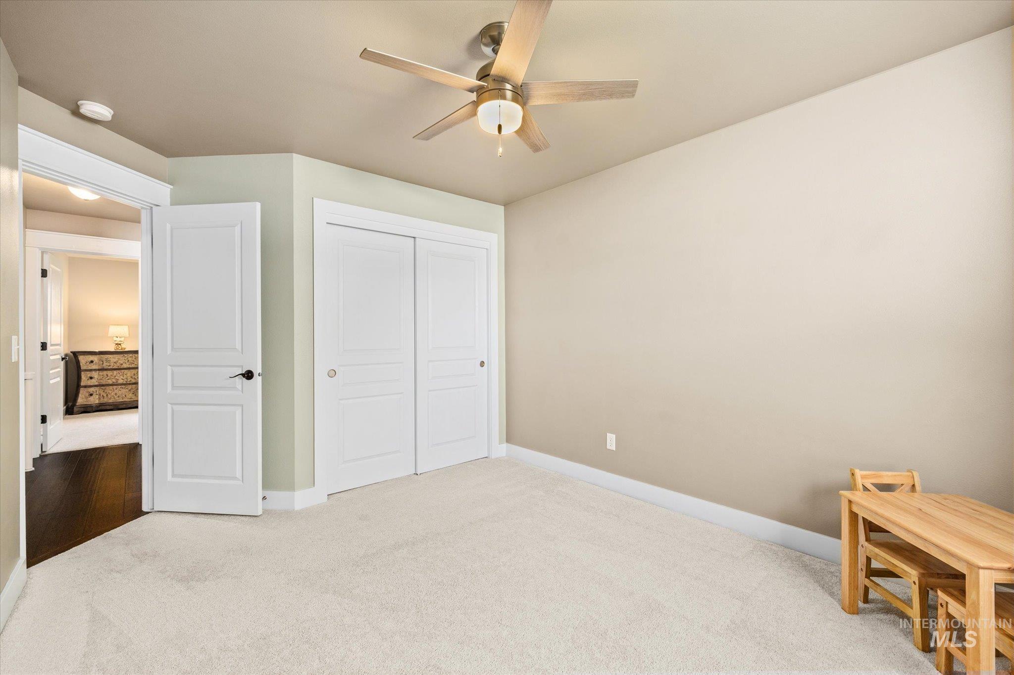 Bedroom with light carpet, a closet, and a ceiling fan