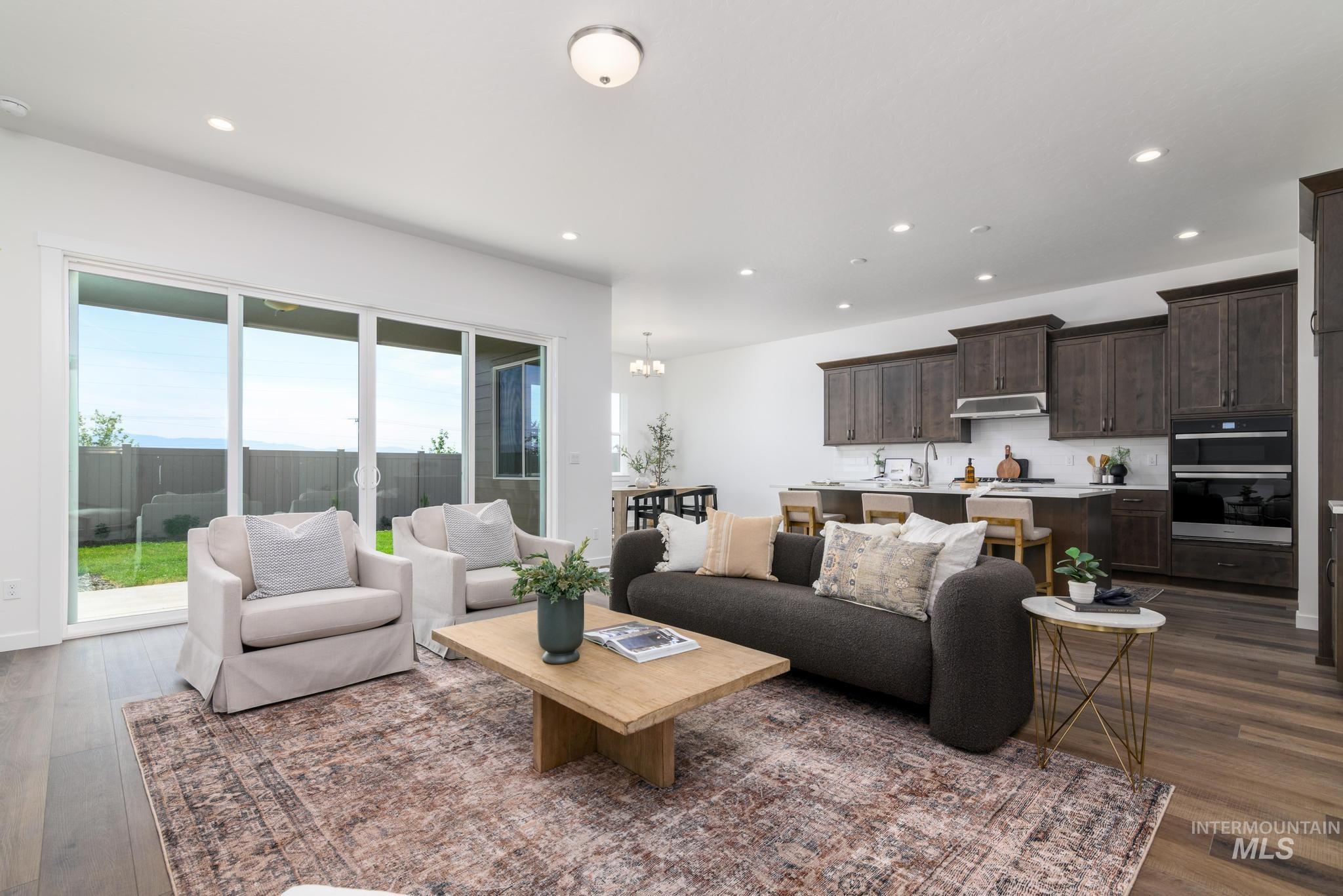Living room featuring dark wood-style flooring, recessed lighting, and a chandelier