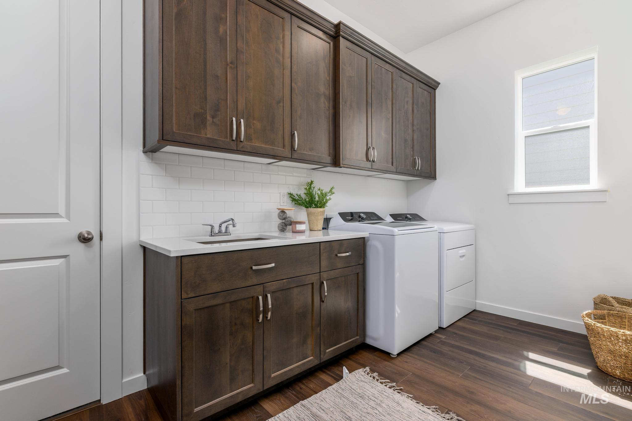 Laundry area featuring dark wood finished floors, washer and dryer, and cabinet space