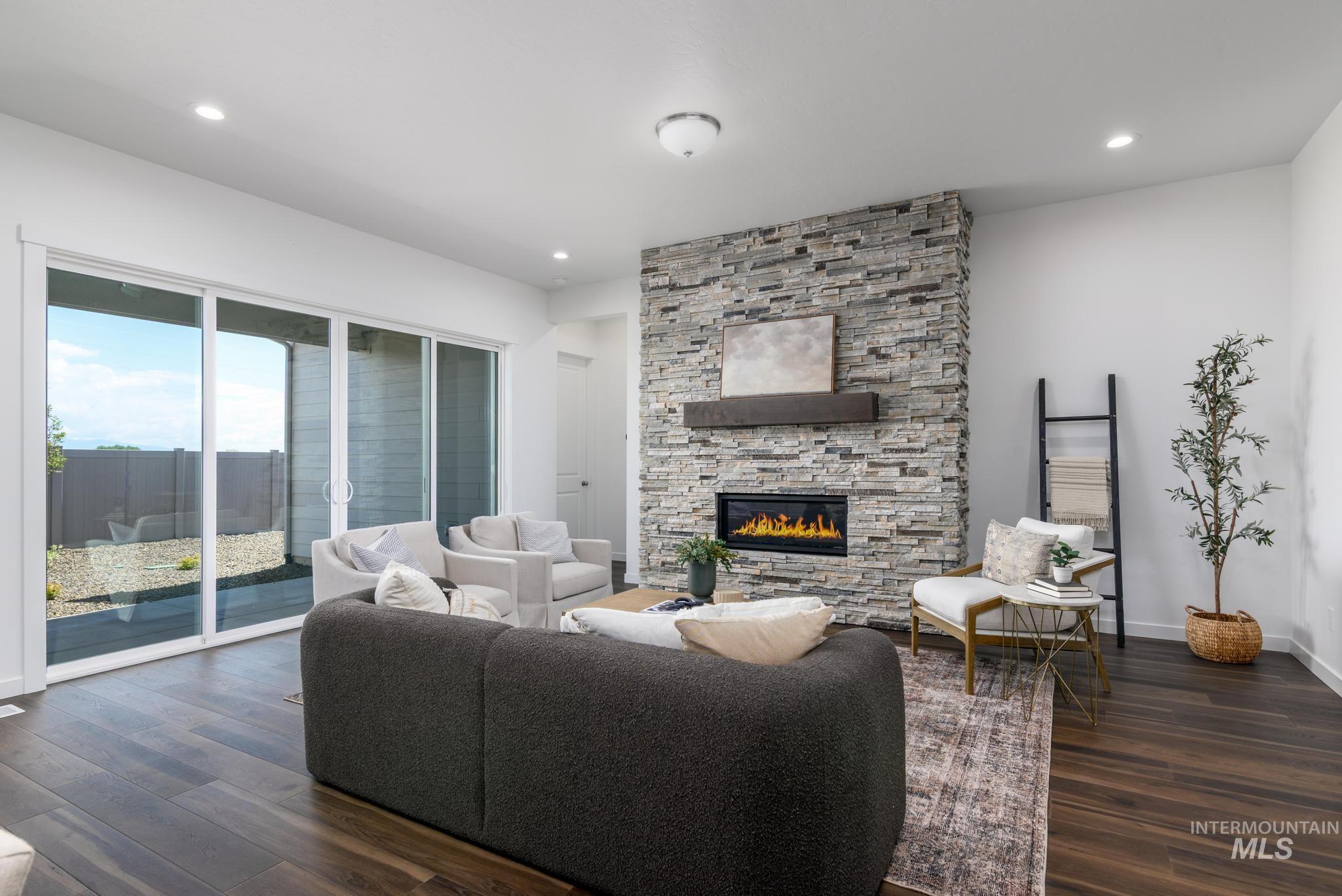 Living area with a stone fireplace, dark wood finished floors, and recessed lighting
