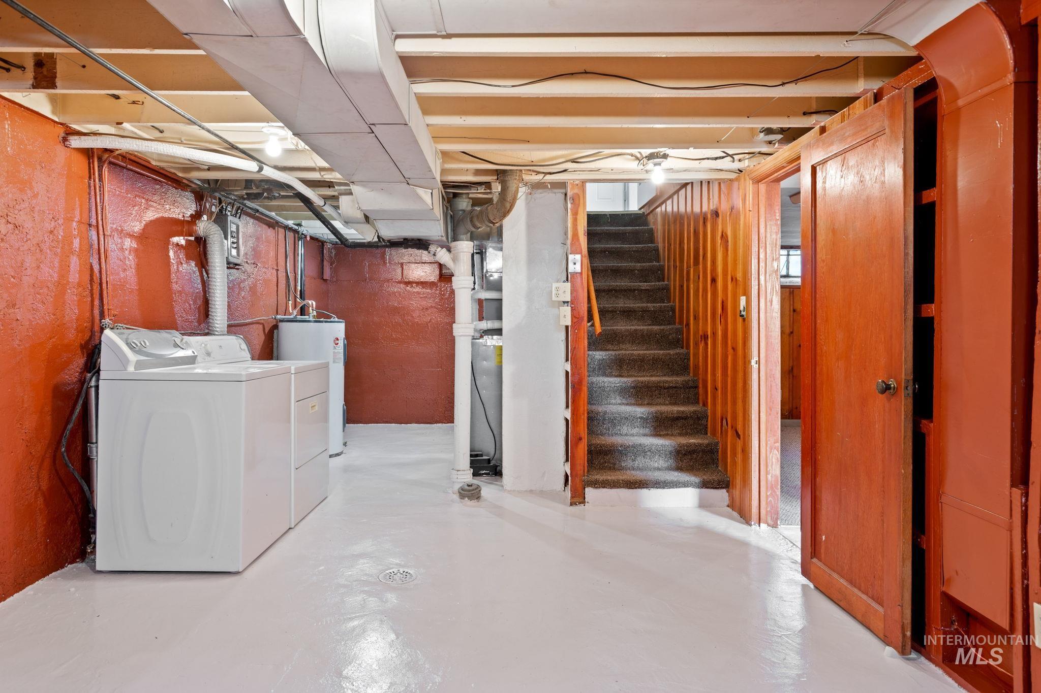 Unfinished basement featuring electric water heater and washing machine and clothes dryer