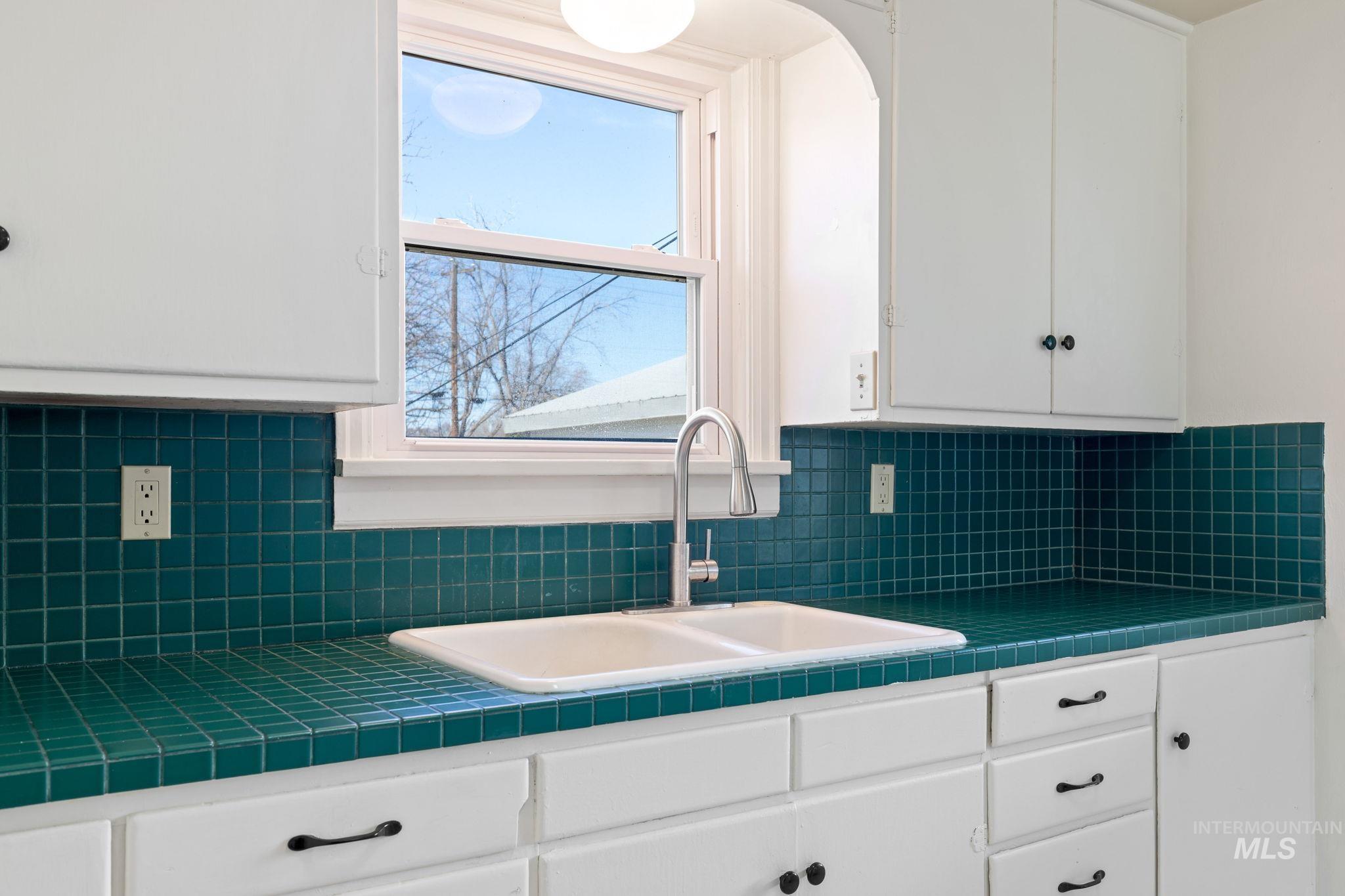 Kitchen featuring tile counters and white cabinets