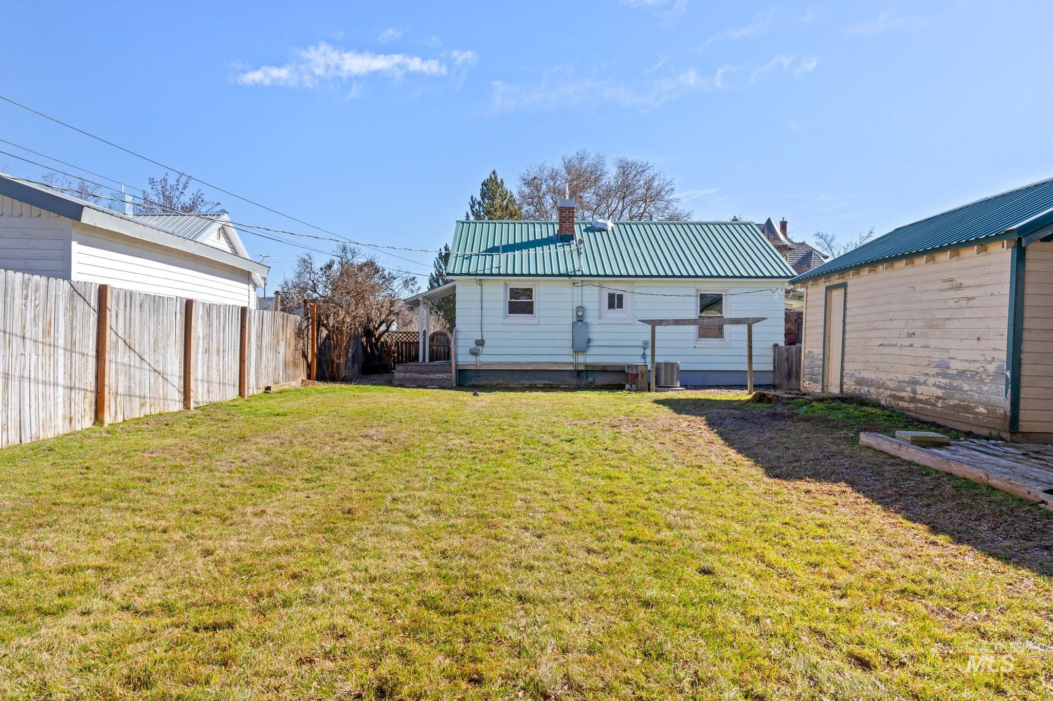Back of house featuring a metal roof, a chimney, and a fenced backyard