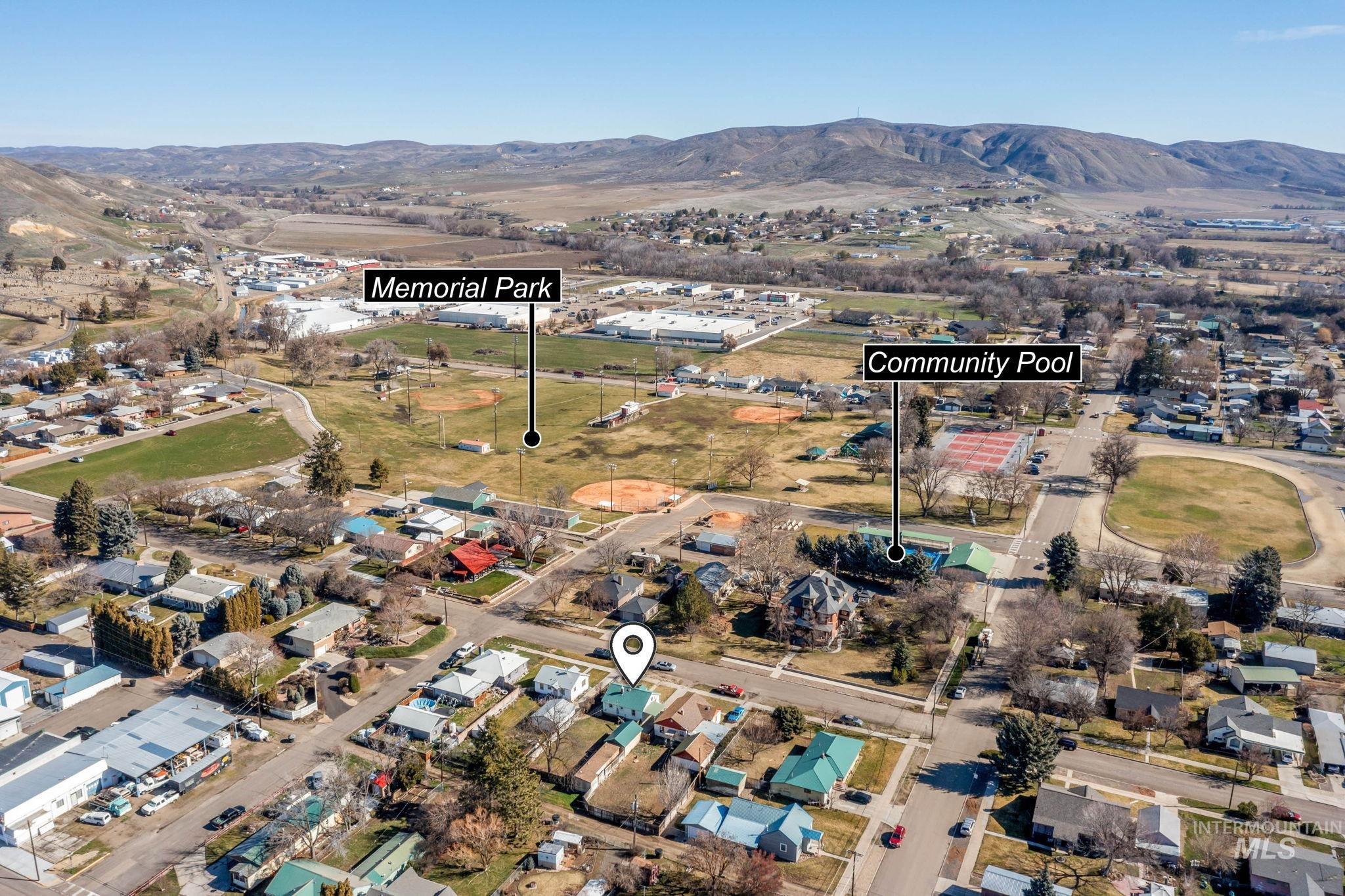 Aerial view of property and surrounding area featuring a mountainous background and nearby suburban area