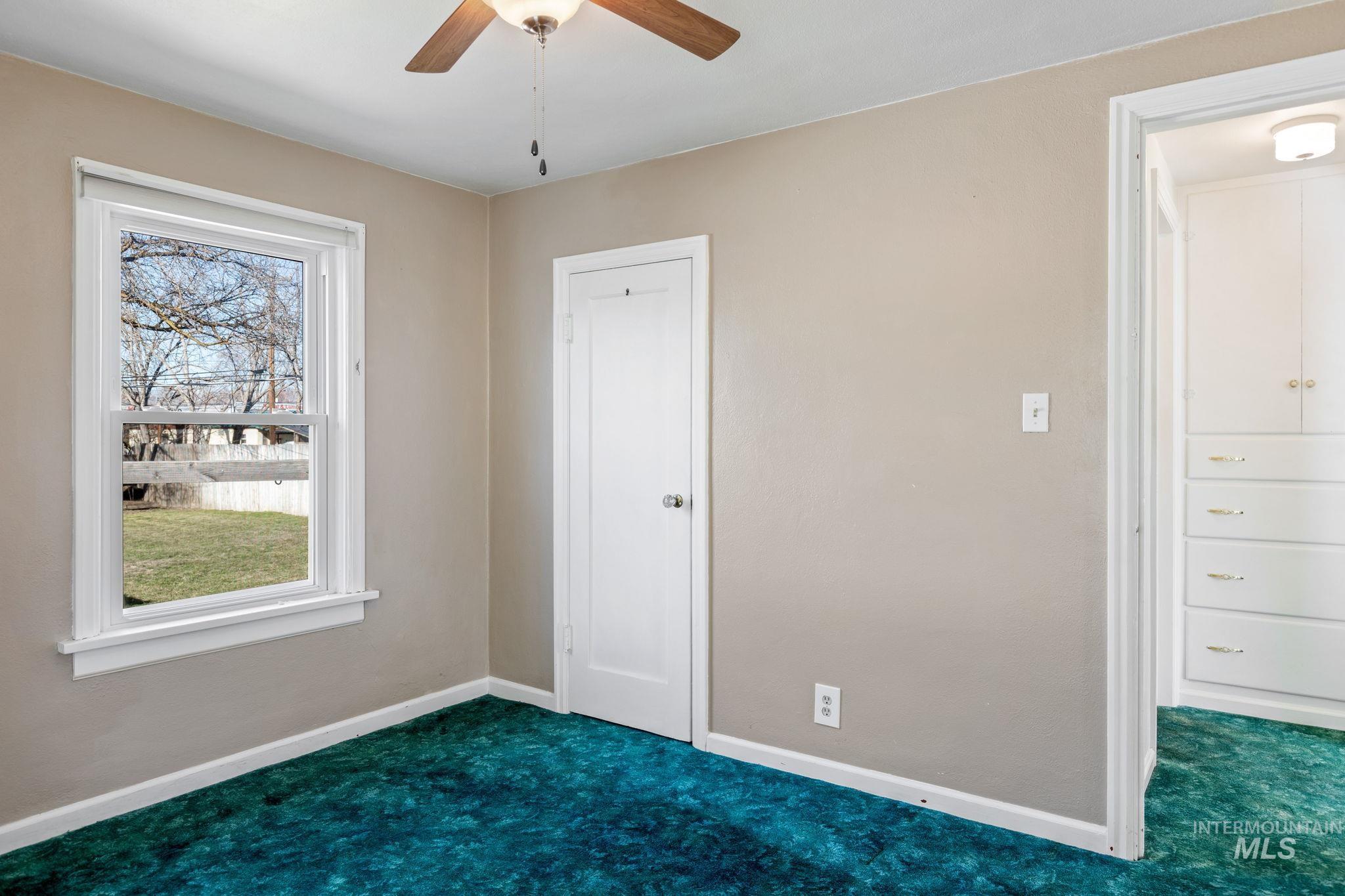 Unfurnished bedroom with a ceiling fan and dark colored carpet