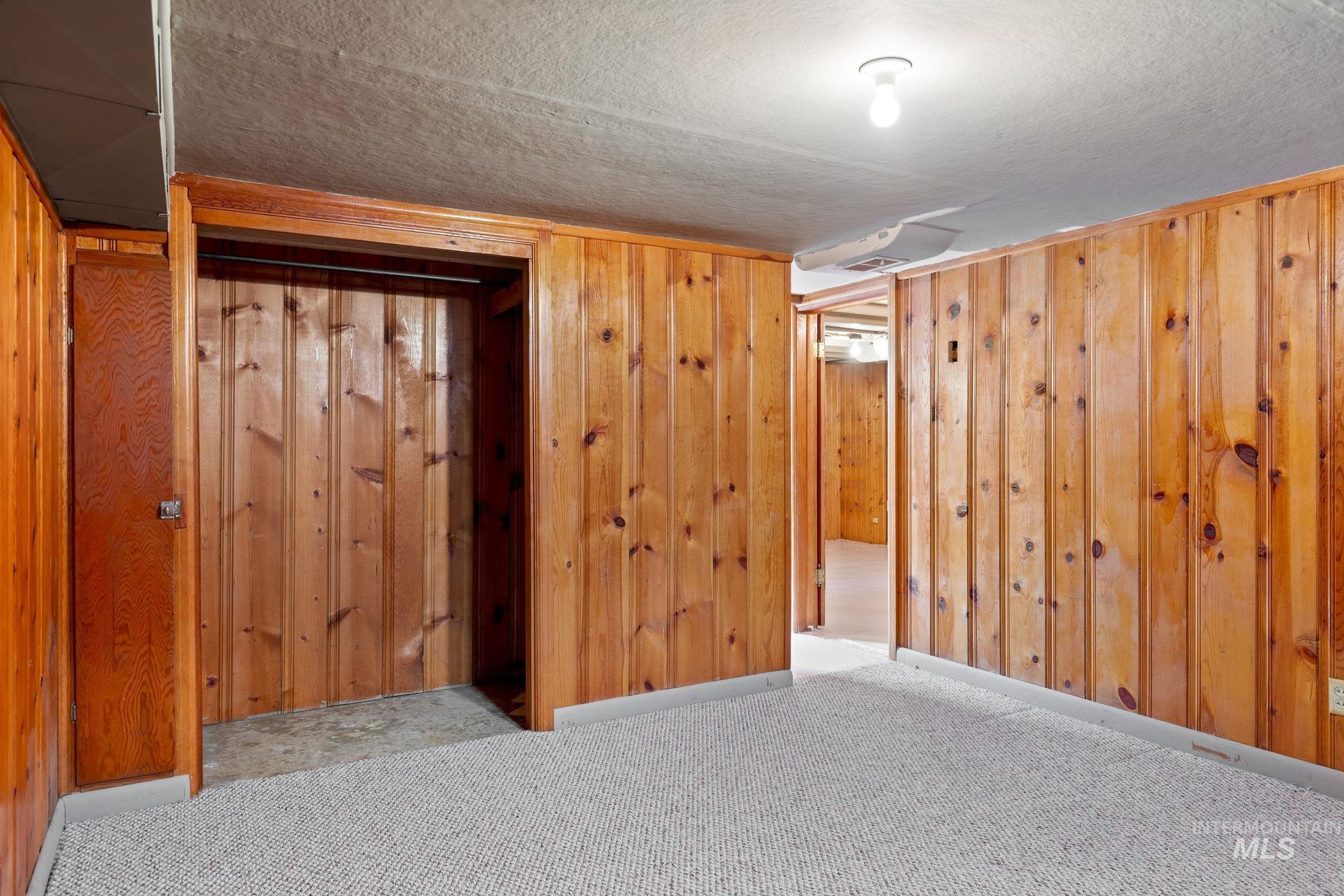 Finished basement with a textured ceiling, carpet floors, and wooden walls