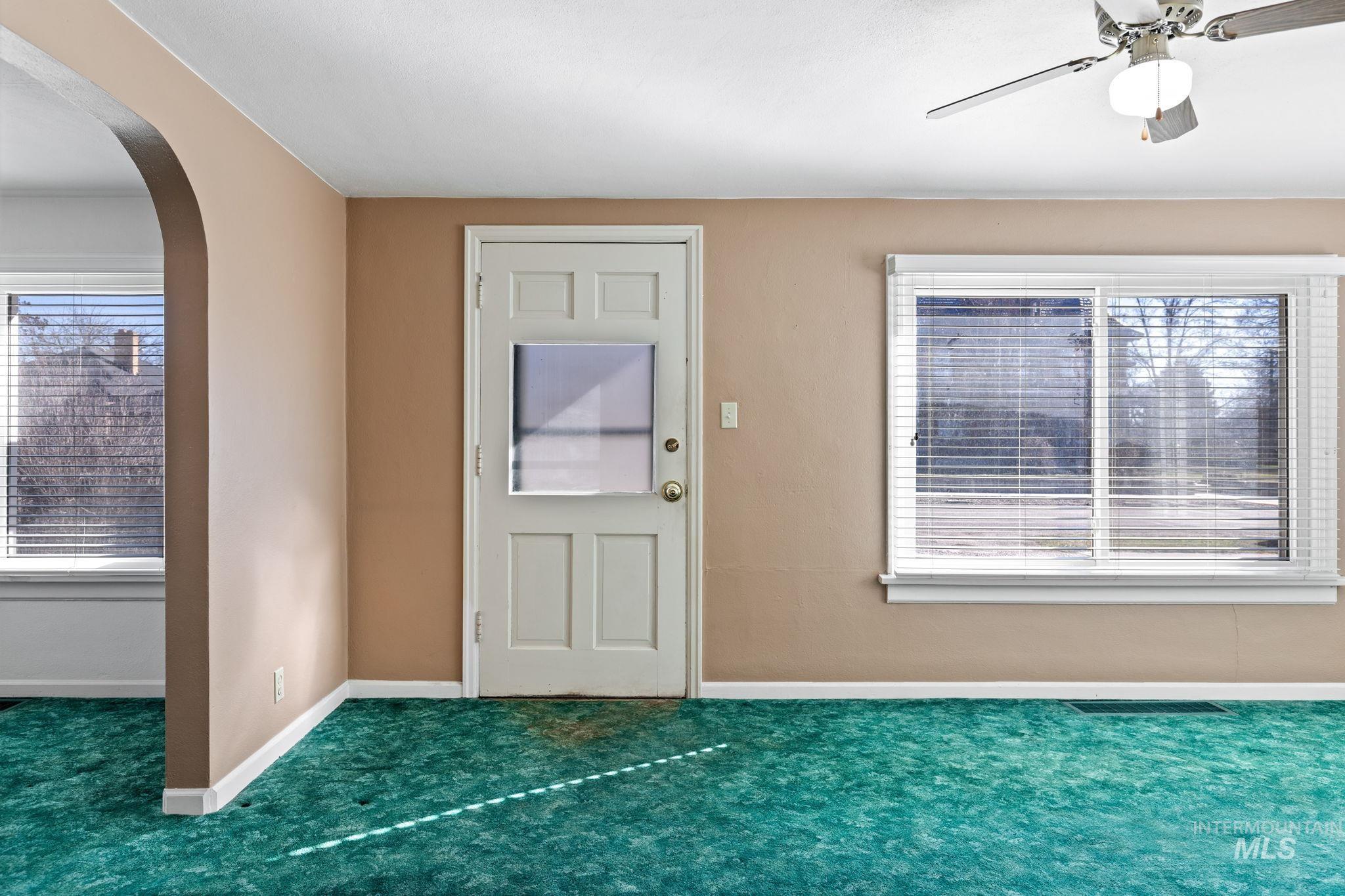 Carpeted entrance foyer featuring arched walkways and a ceiling fan