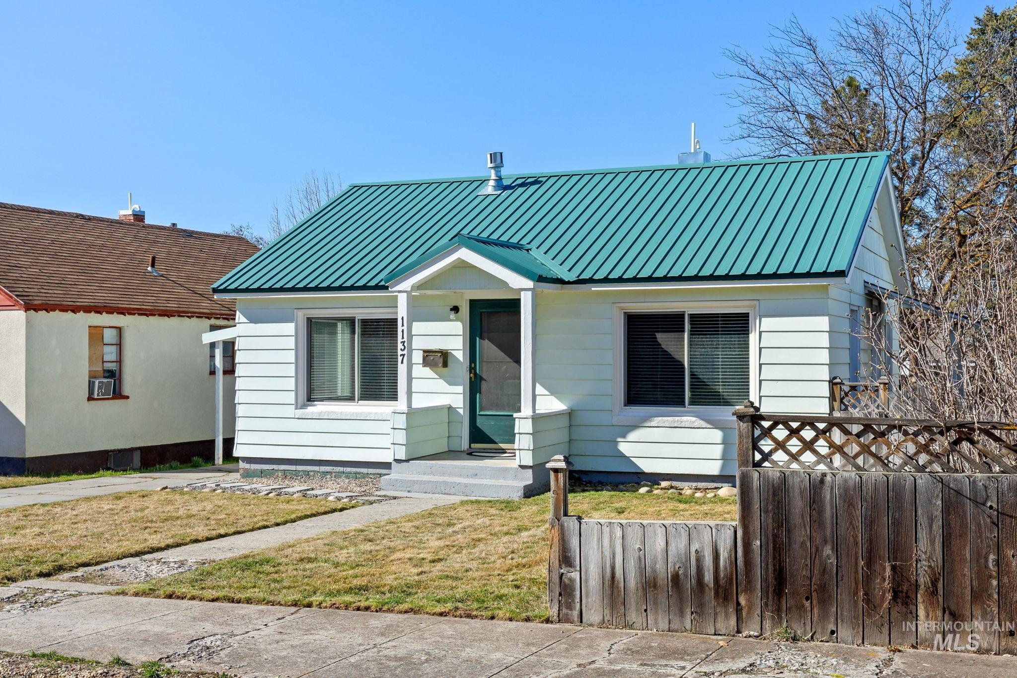 Bungalow-style house with a fenced front yard and a metal roof