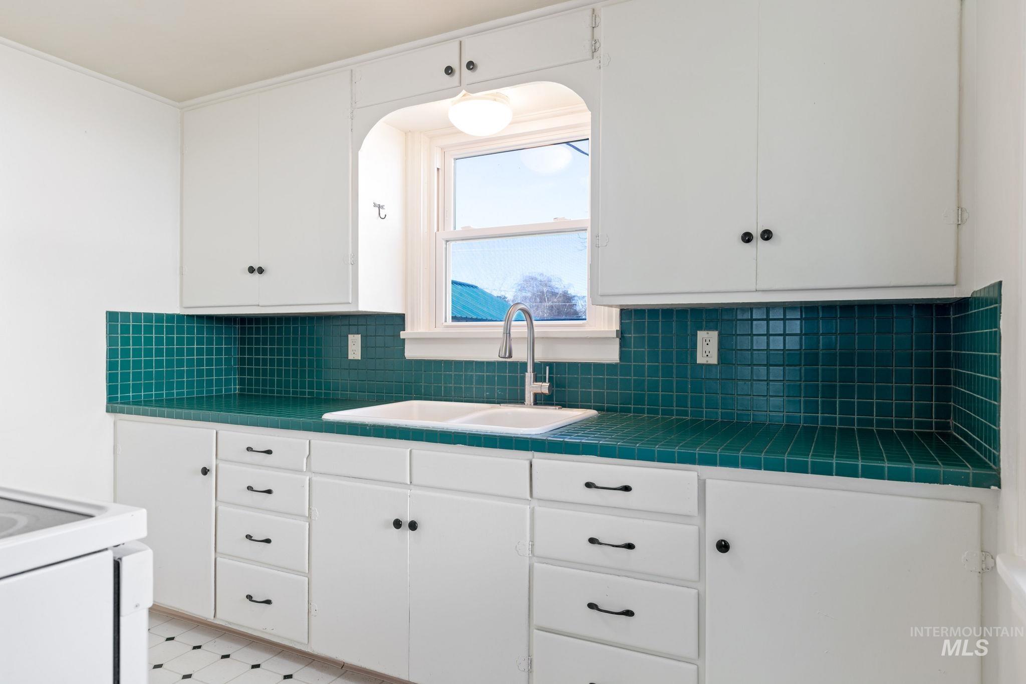 Kitchen featuring tile countertops, white cabinets, light floors, and white range