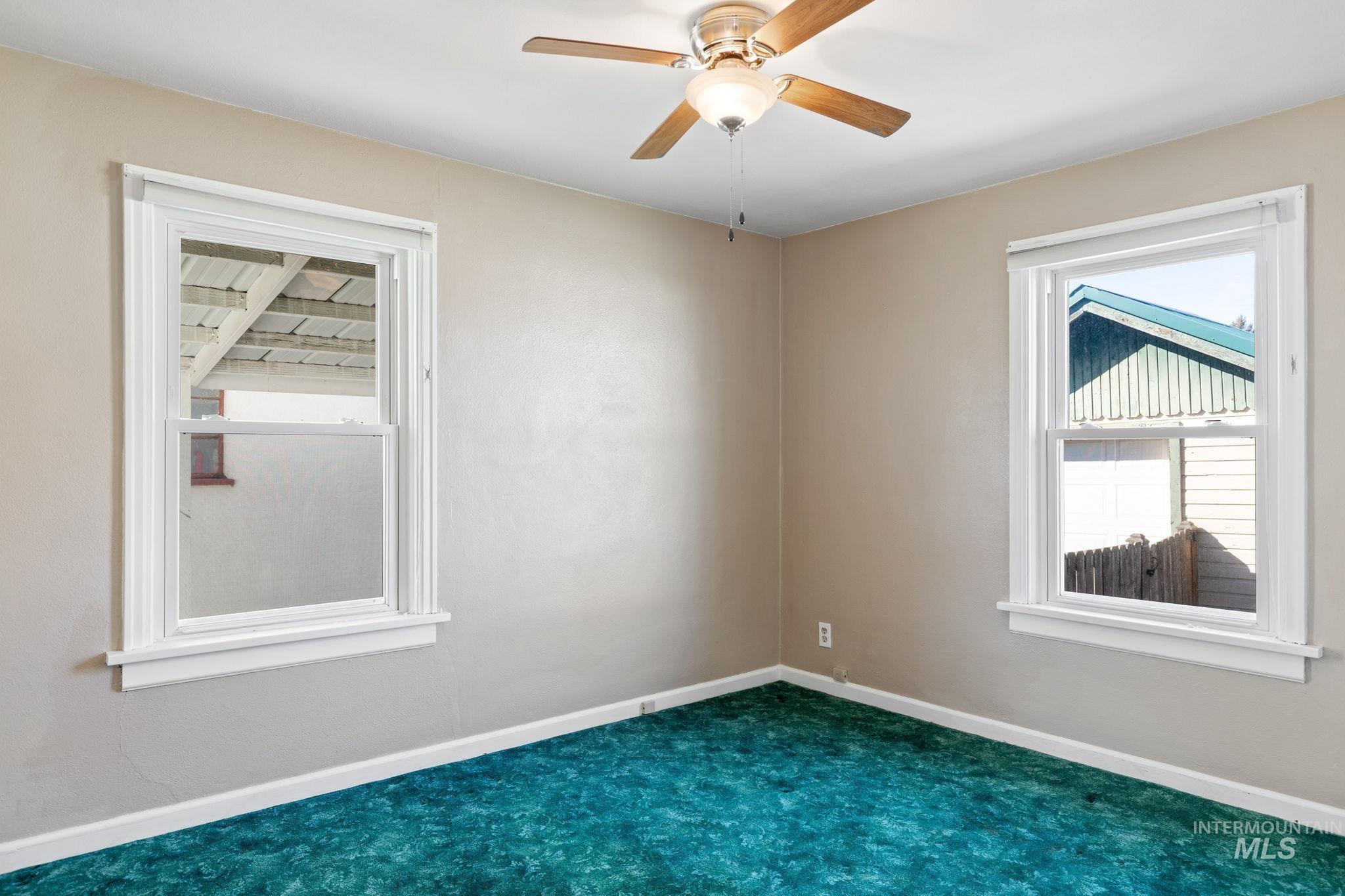 Unfurnished room with a ceiling fan and dark carpet