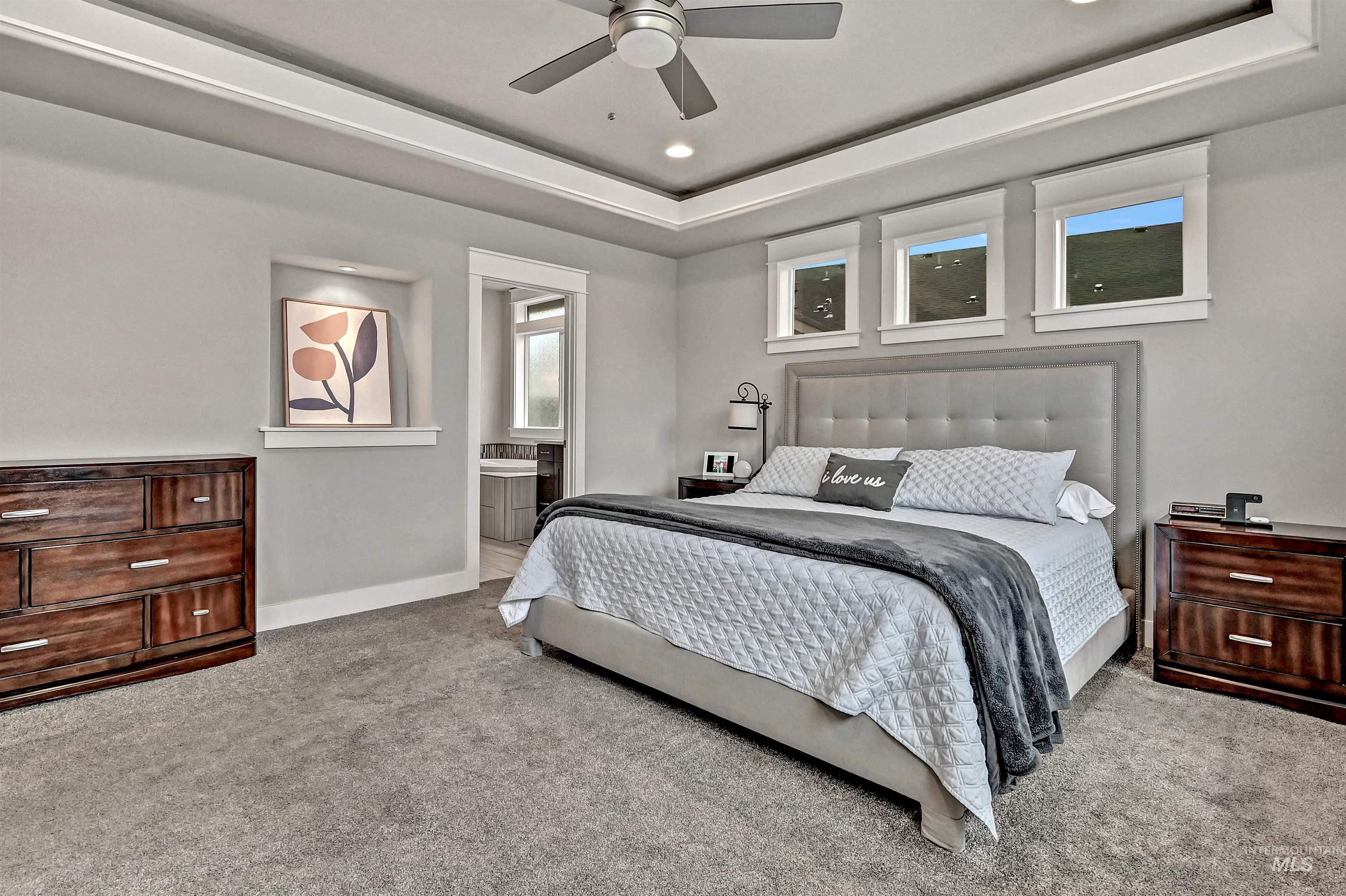 Primary bedroom with light colored carpet, recessed lighting, a ceiling fan, and a tray ceiling