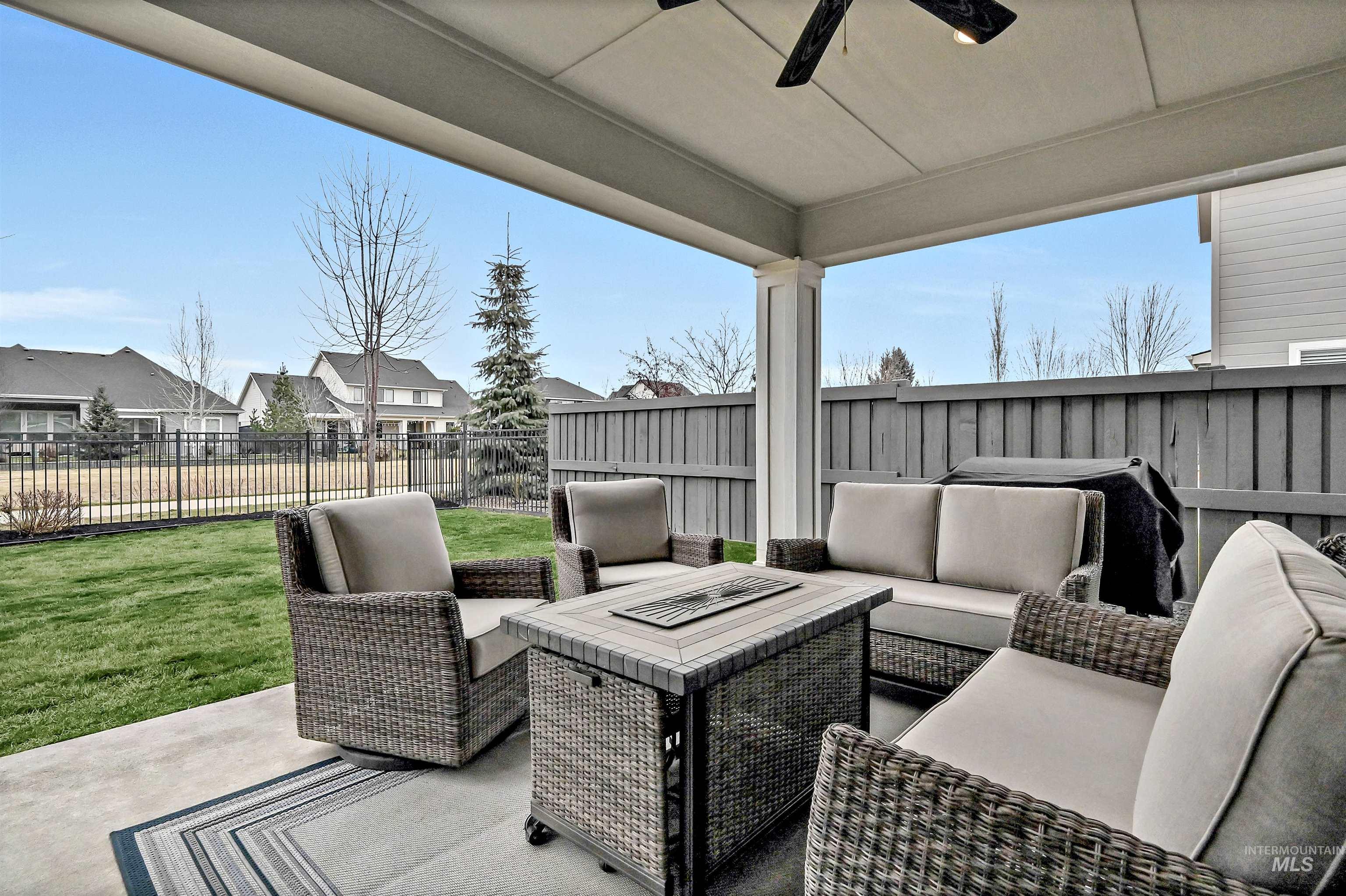 Fenced backyard featuring a patio area, covered outdoor lounge area, a ceiling fan, and a residential view