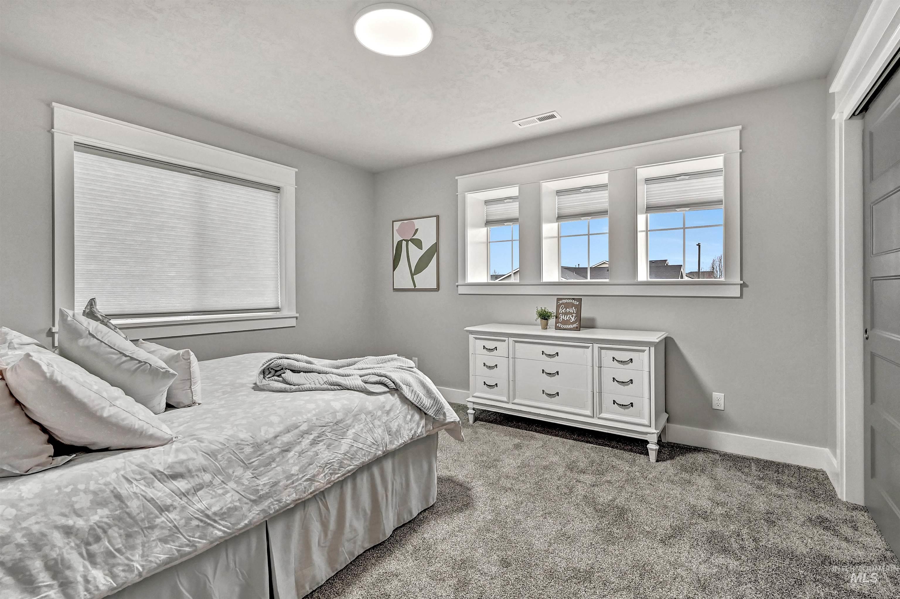 Bedroom featuring light carpet and expansive windows