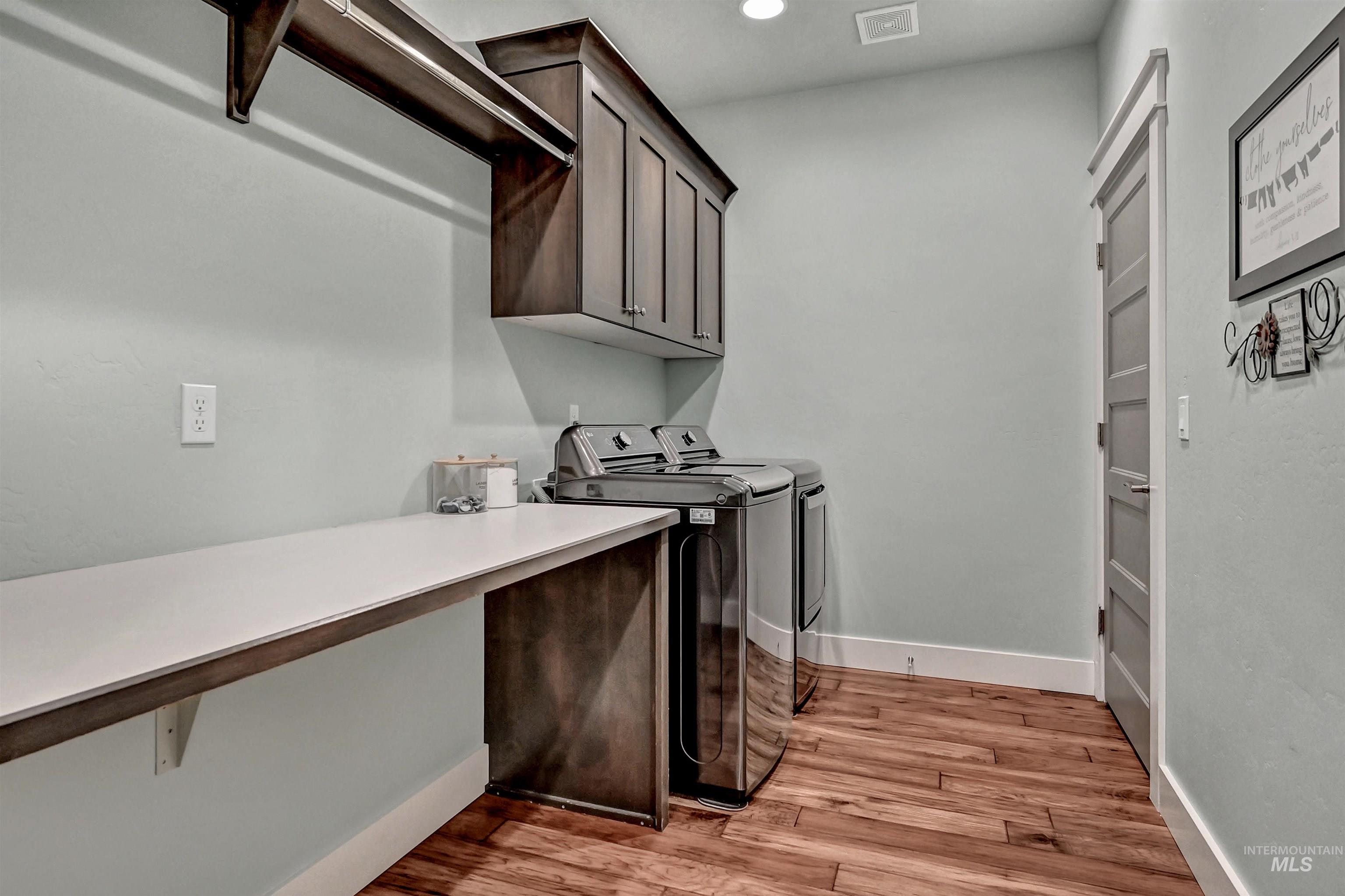 Laundry room connected to the primary bedroom walk-in closet, large counter space, dark cupboards, and a hanging rod