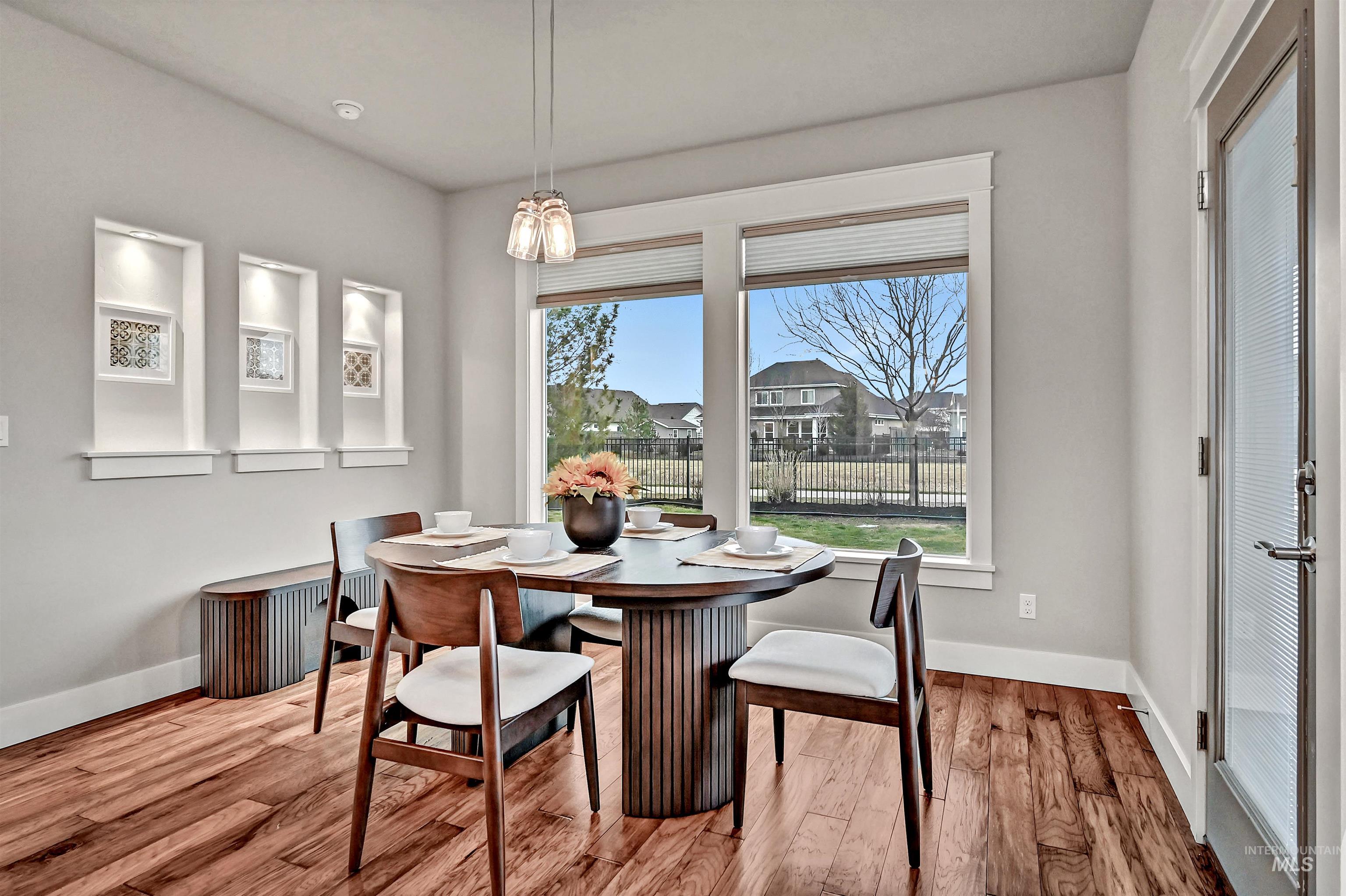 Dining area with engineered wood floors, large windows, and a door out to the covered patio
