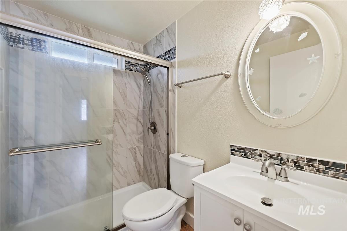 Full bath featuring tasteful backsplash, vanity, a textured wall, and a shower stall