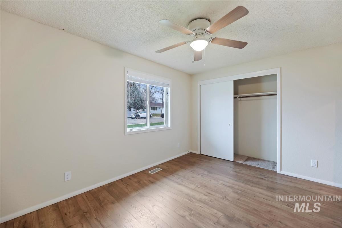 Unfurnished bedroom with a ceiling fan, a textured ceiling, a closet, and light wood finished floors